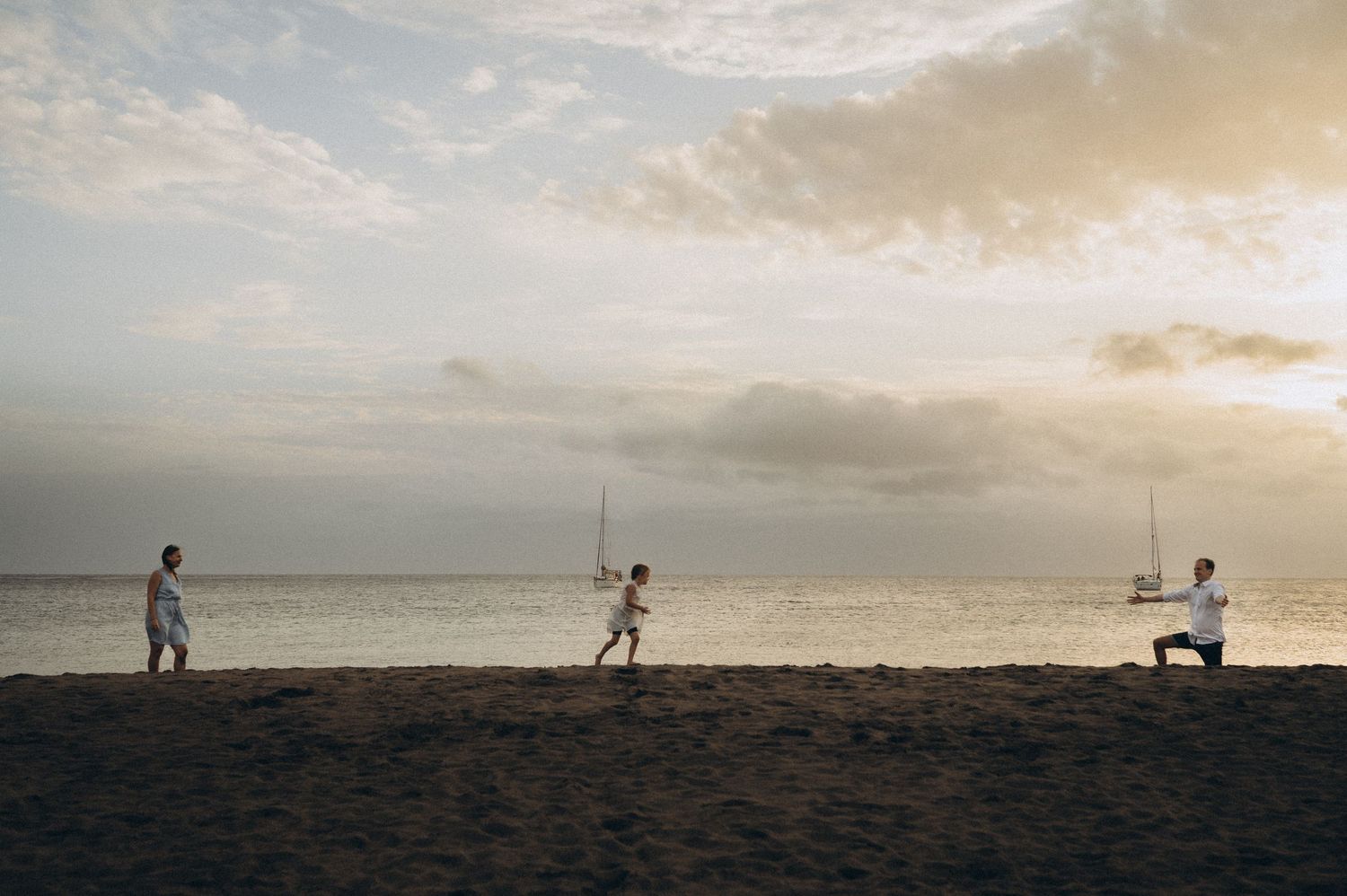 Silhouetted figures walk along a beach horizon at sunset with dramatic cloudy skies.