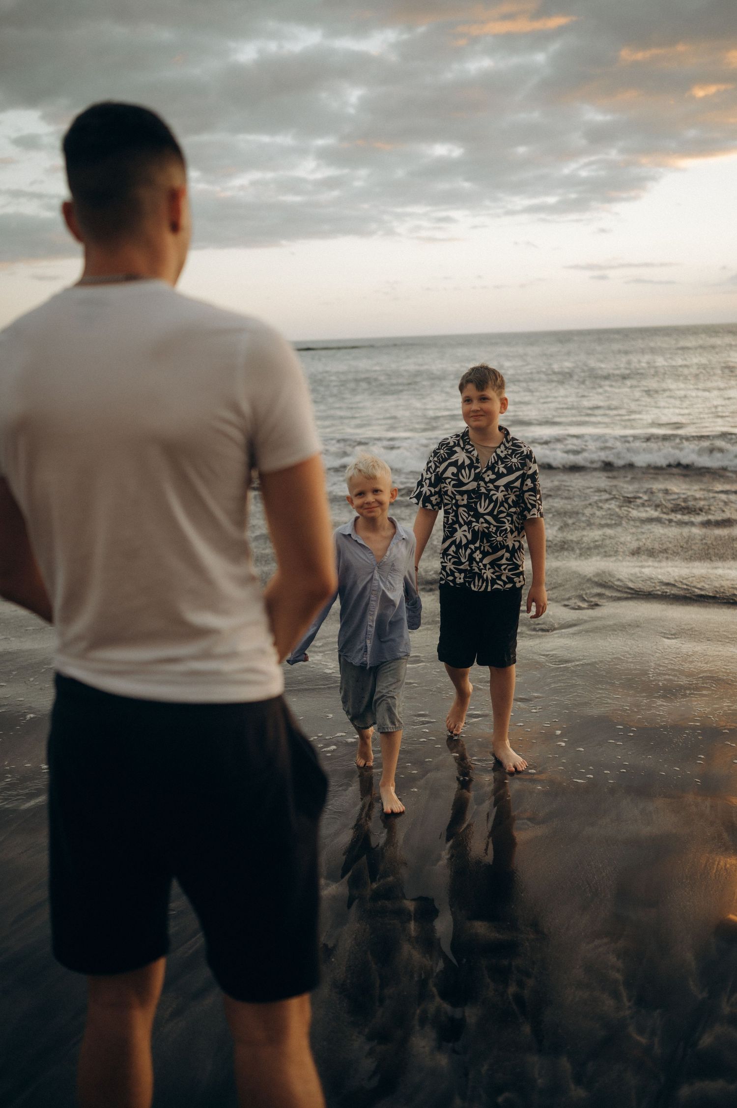 Older brother watching two younger brothers walking together on Playa Fañabé