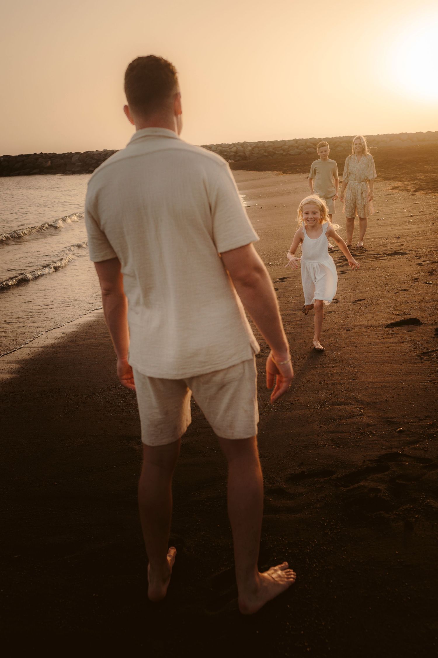 Father watching his family play on beach at sunset, Tenerife