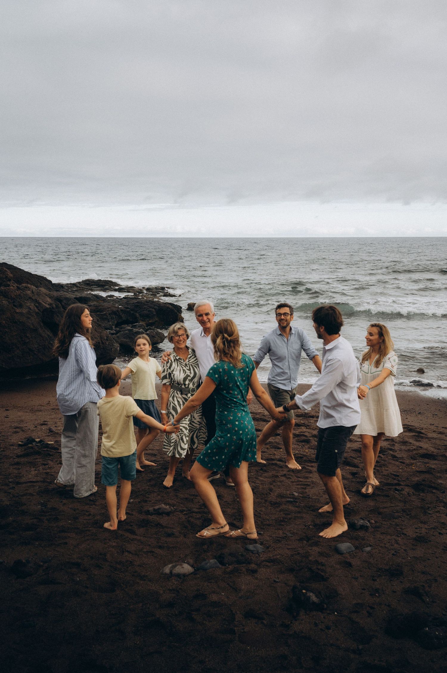 Grandparents standing in center of circle formed by family holding hands and spinning at Los Refugios
