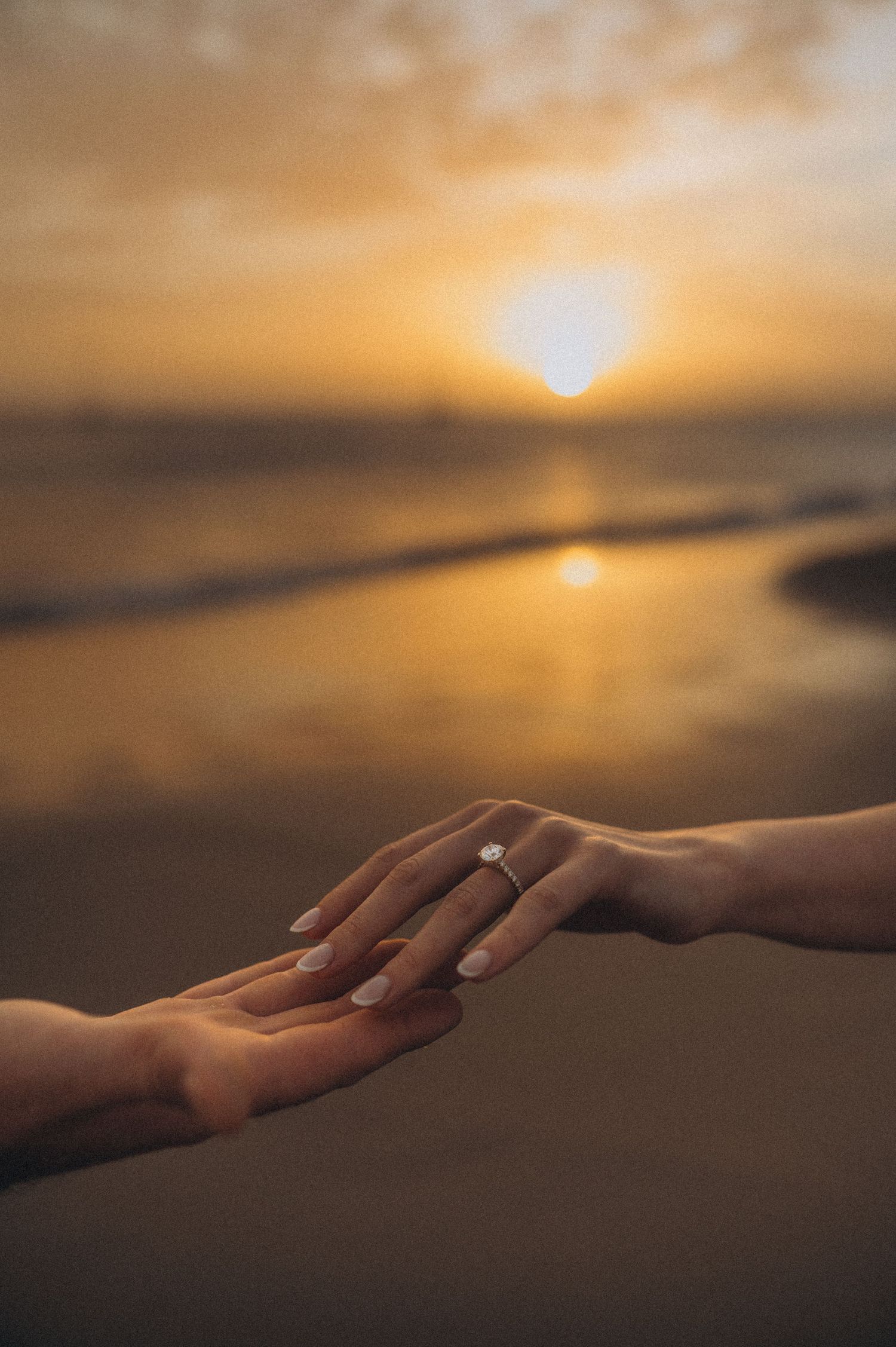 Tender fingertip touch of couple’s hands with Atlantic Ocean behind, Playa de La Tejita, Tenerife