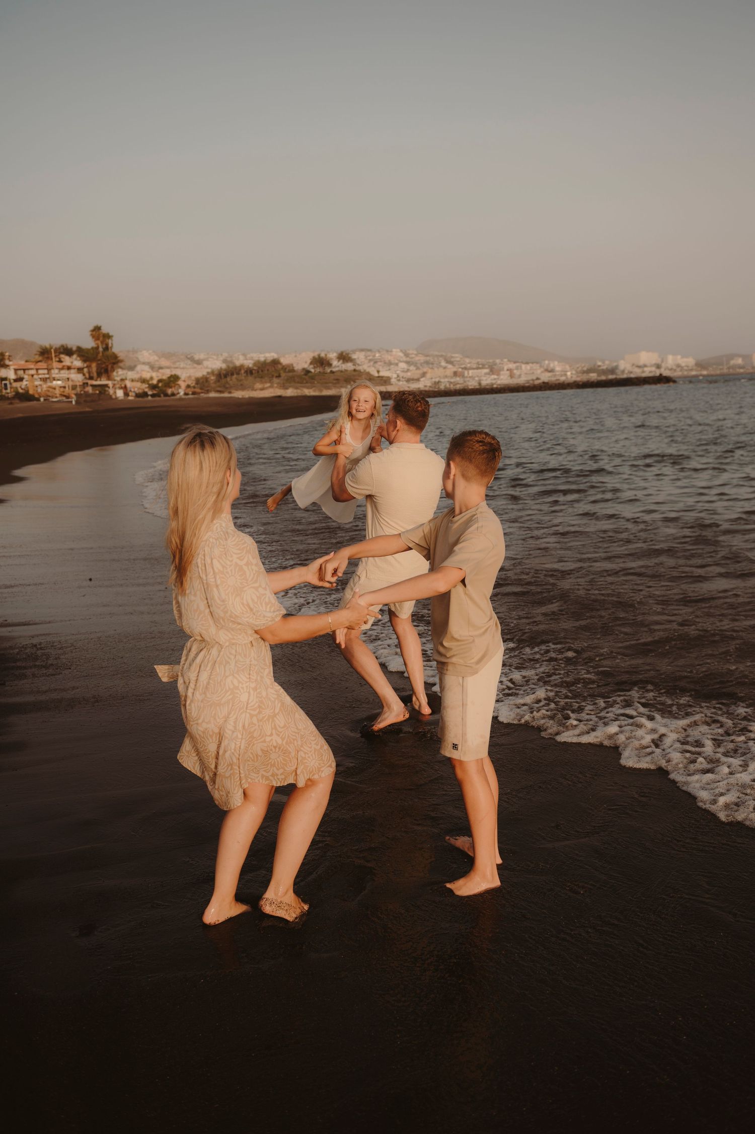 Joyful family moment by ocean during sunset, Tenerife