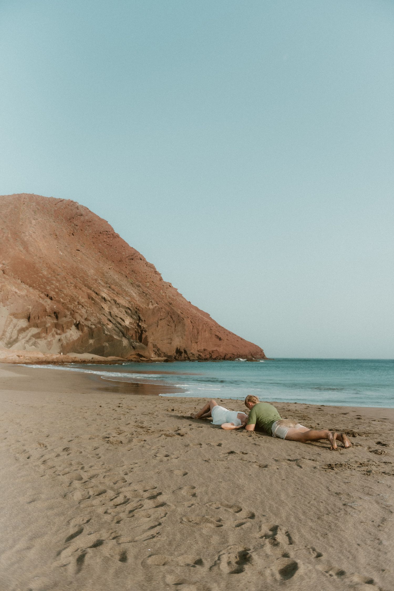 Young couple lying in the sand and enjoying a romantic moment on Playa Tejita with Montaña Roja in the background, Tenerife couples photosho