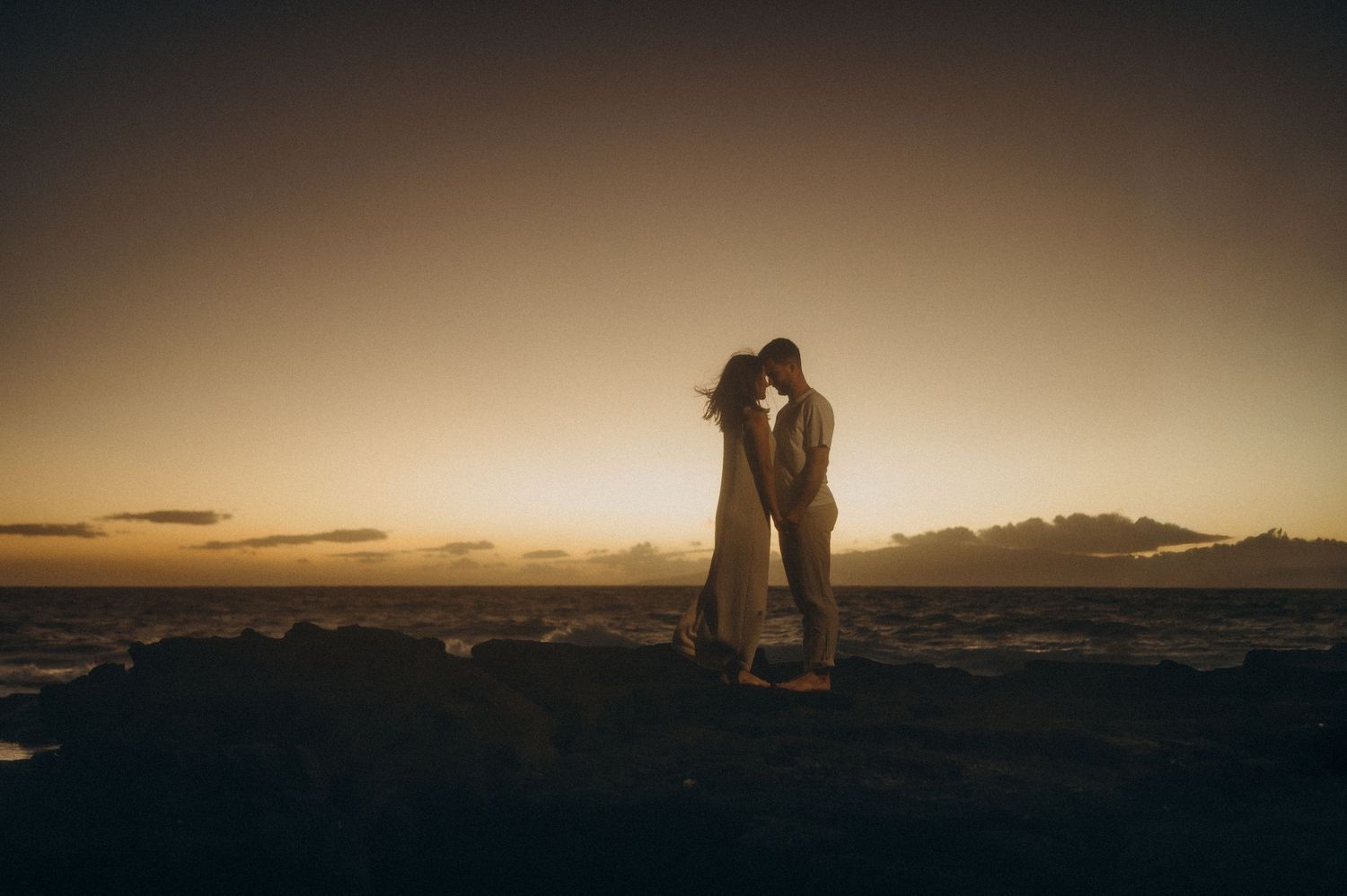 Romantic couple standing face-to-face on south Tenerife beach with soft night lighting