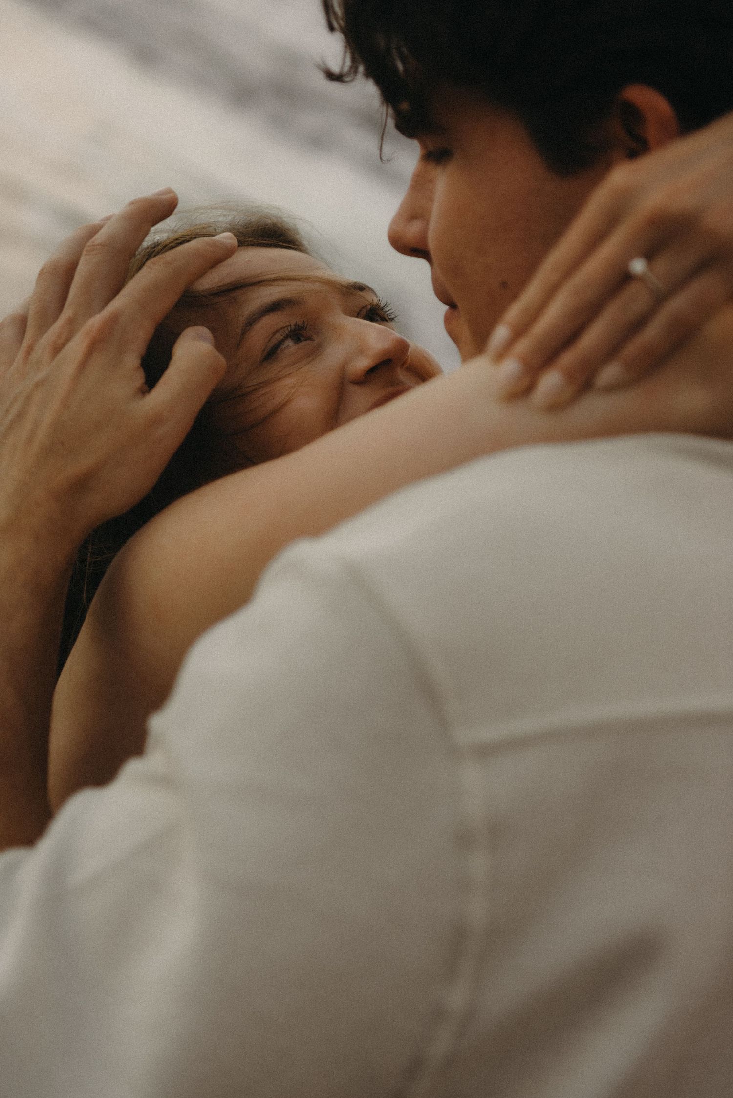 A couple shares an intimate moment, with a man gently holding a woman's face as she gazes up at him tenderly.