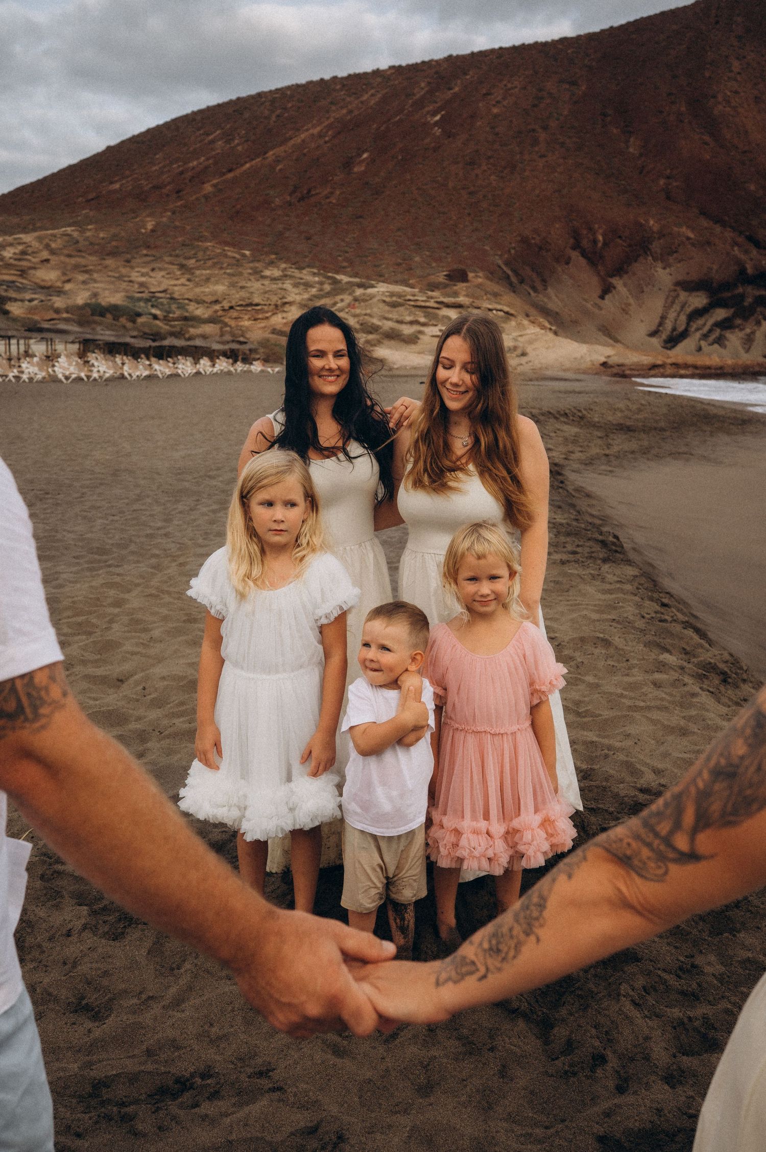 Close-up of parents holding hands with family standing behind, watching them, Playa La Tejita