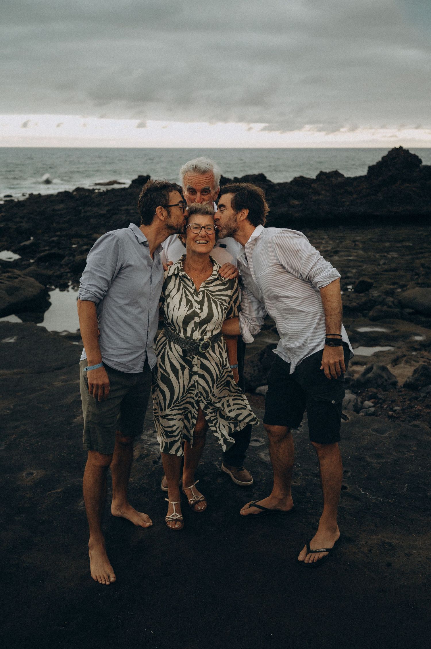 Mother kissed by husband and two sons with volcanic coast and Atlantic view in Tenerife