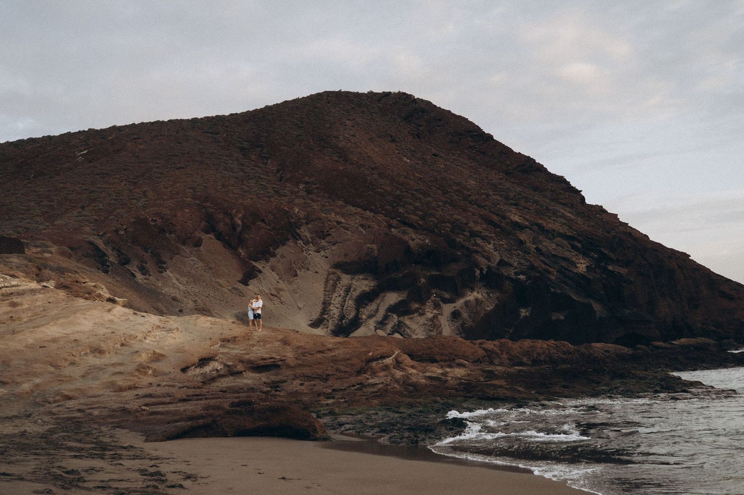 Panoramic view of rugged coastal cliffs and rocky shoreline against cloudy sky in Tenerife.