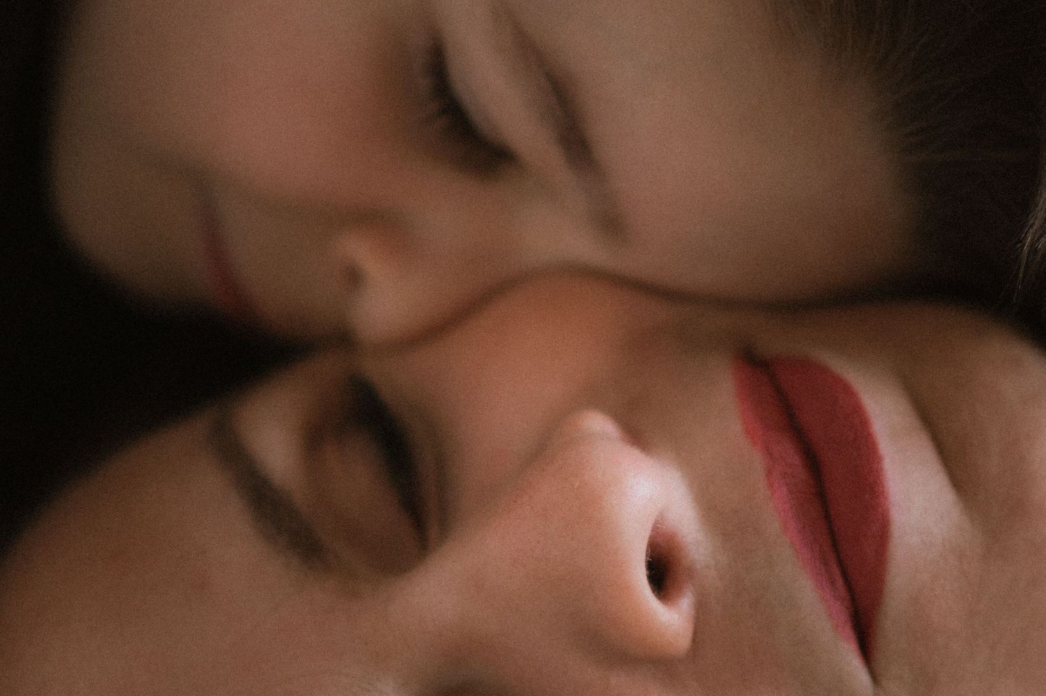 Mother and young son lying next to each other, sharing intimate cheek-to-cheek contact