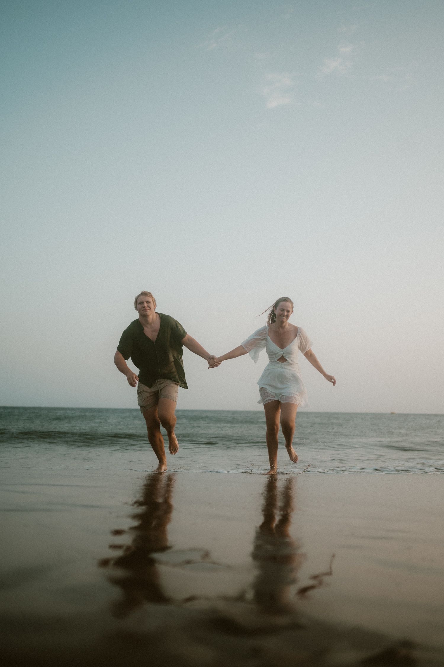 Young couple running hand in hand on Playa Tejita, Tenerife couples photoshoot by the beach