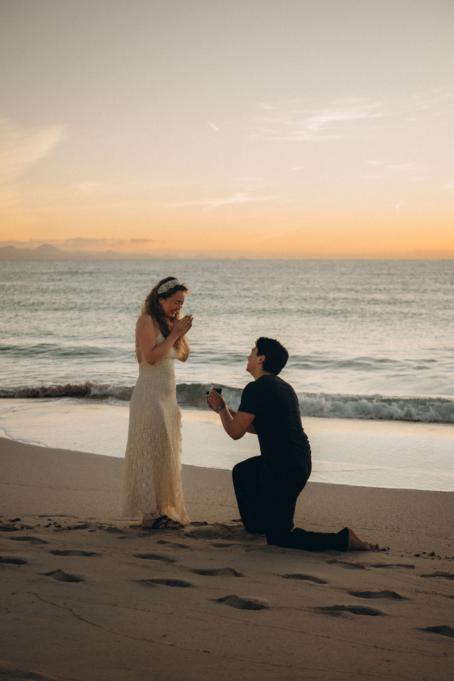 Surprise proposal in Fuerteventura at Dunas de Corralejo beach at sunset with joyful reaction and ocean waves in the background.