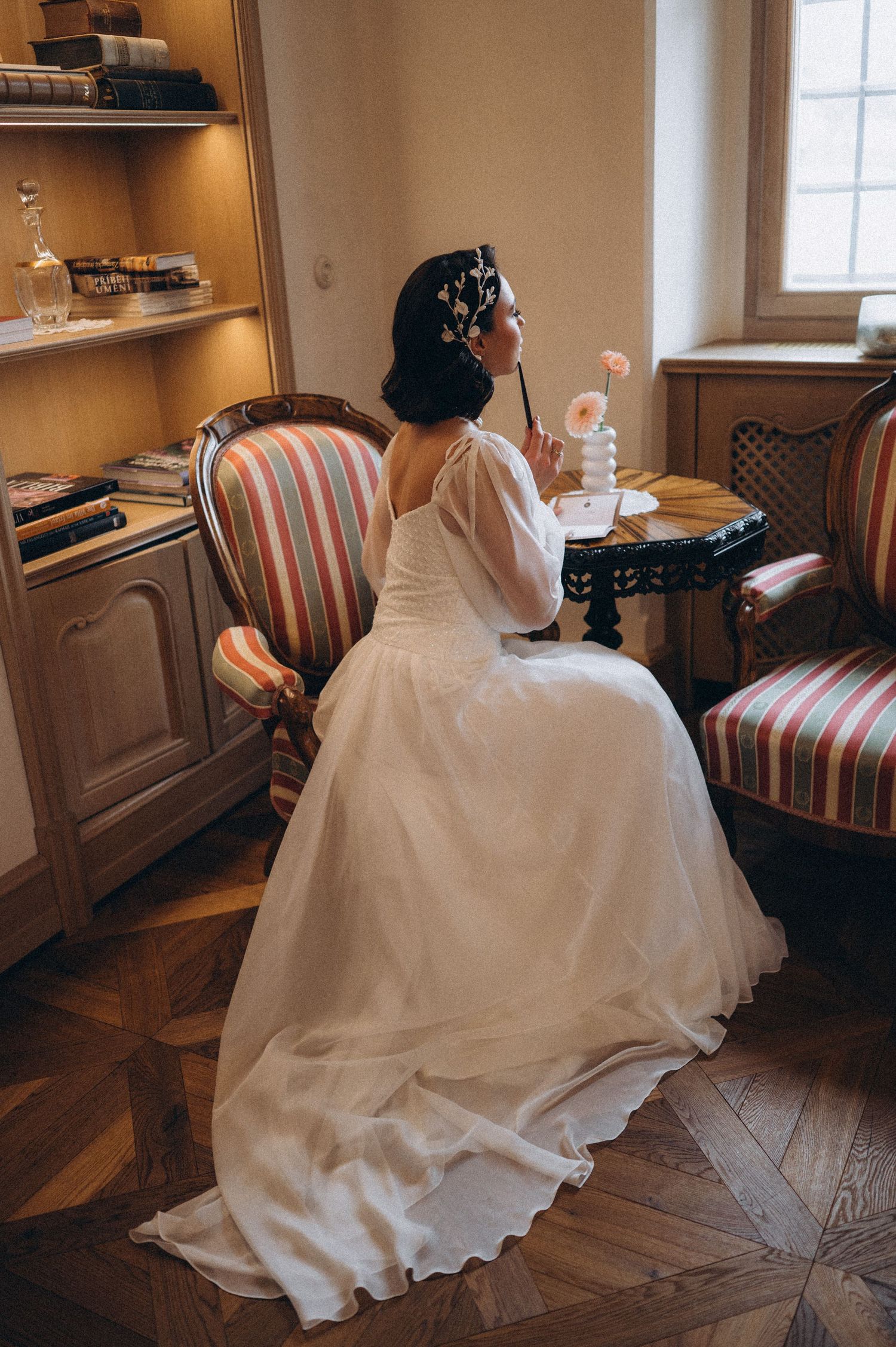 Bride seated in an ornate chair at a wedding table, preparing her vows during a quiet wedding moment.