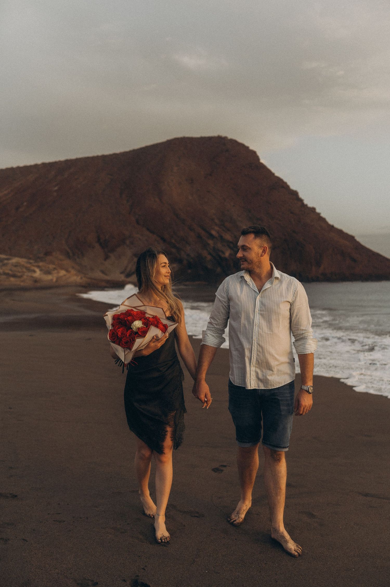 Romantic moment of couple toasting champagne after proposal on Playa de La Tejita, Tenerife