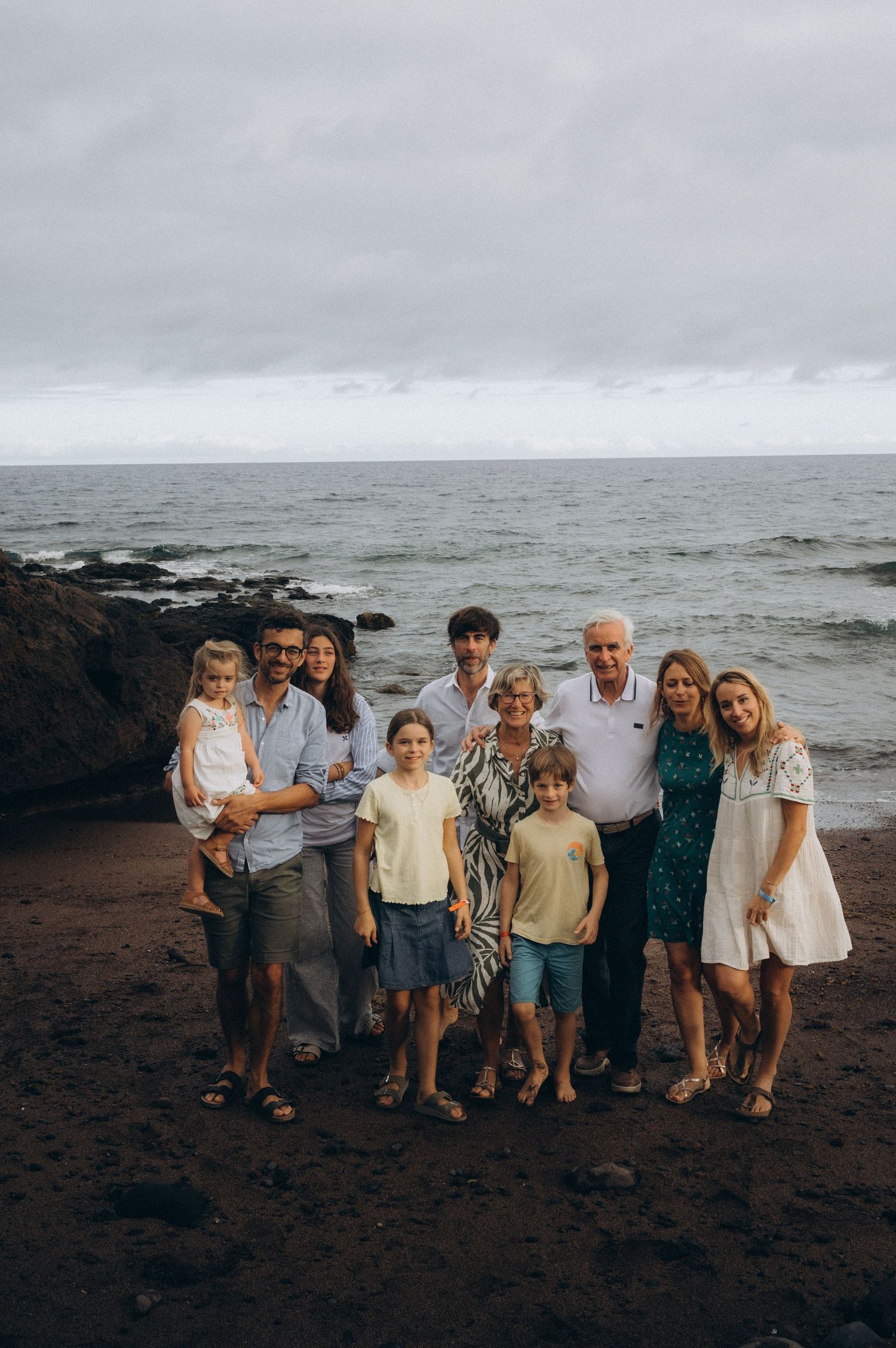 Grandparents, parents, and children walking together from ocean on black sand at Los Refugios, Tenerife