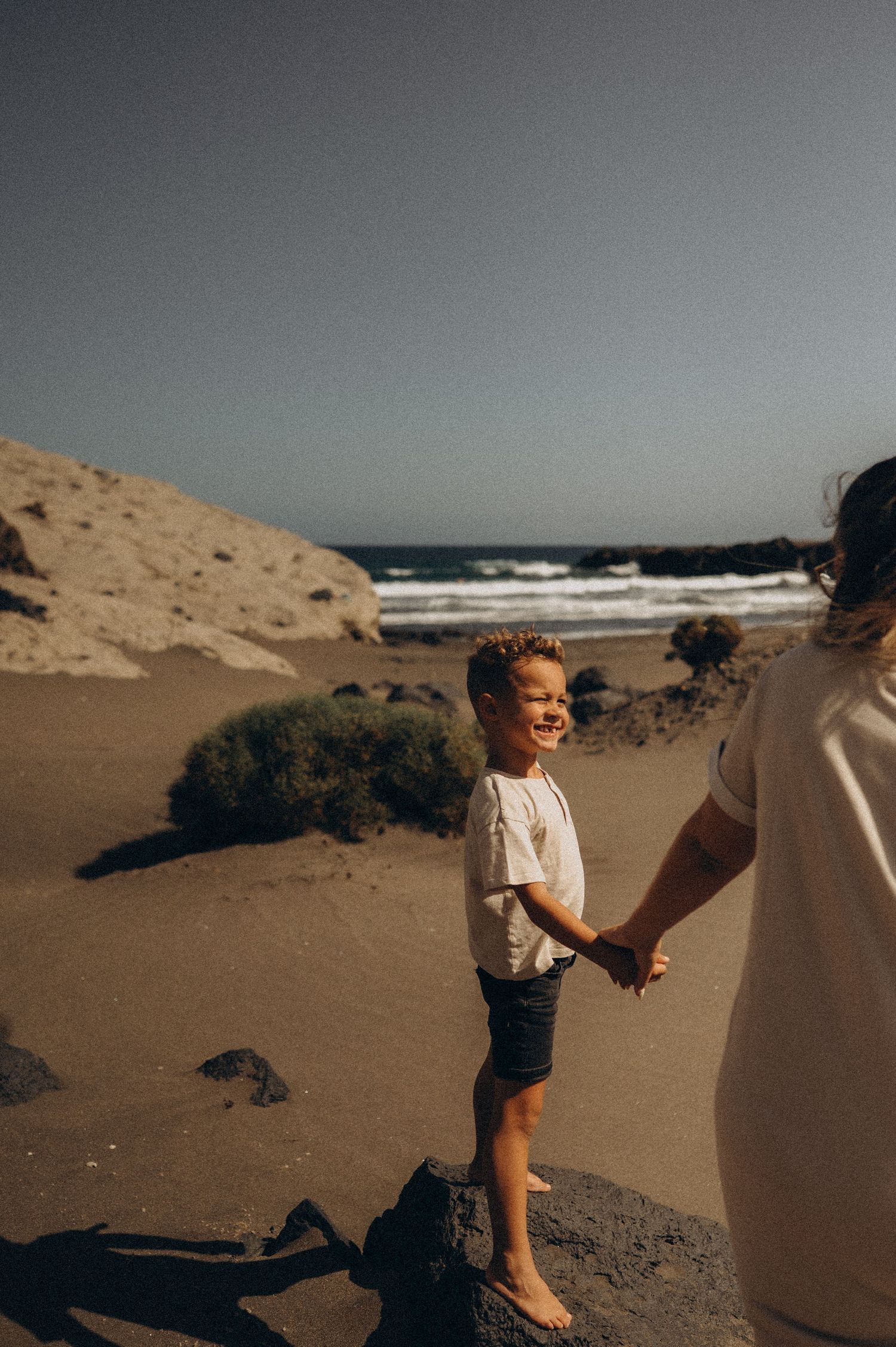 Sunset moment with little boy holding mother’s hand by ocean on Playa Montaña Pelada Tenerife