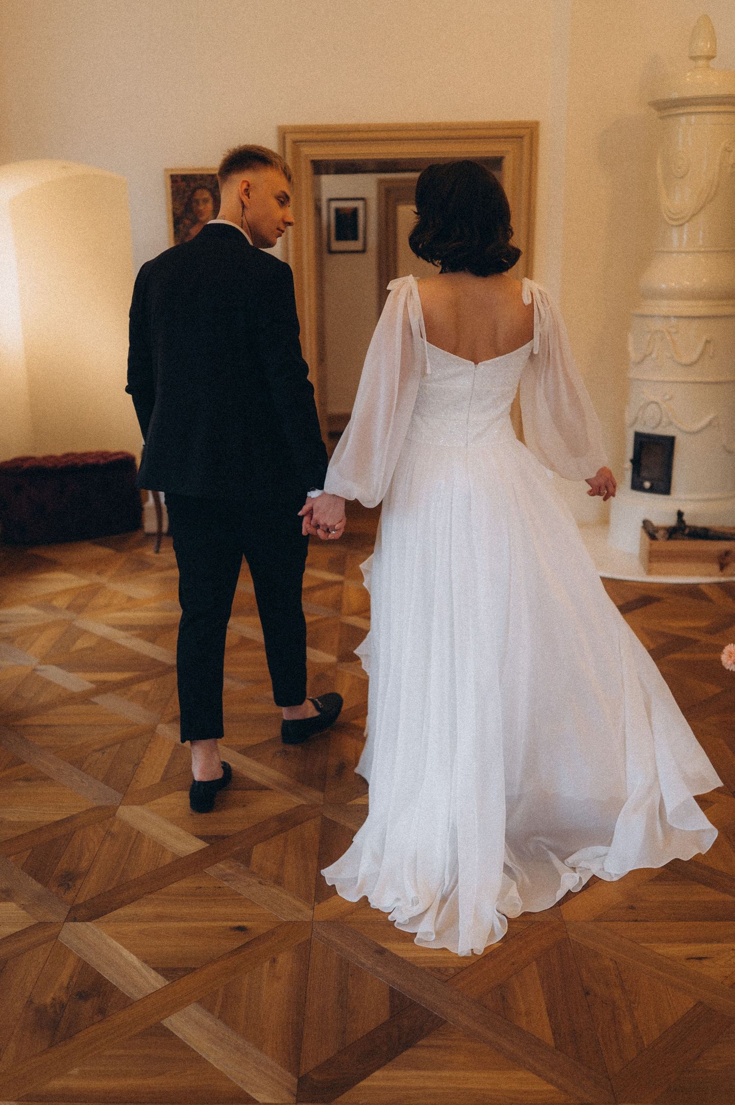 Bride and groom walking hand in hand through a grand wedding hall.