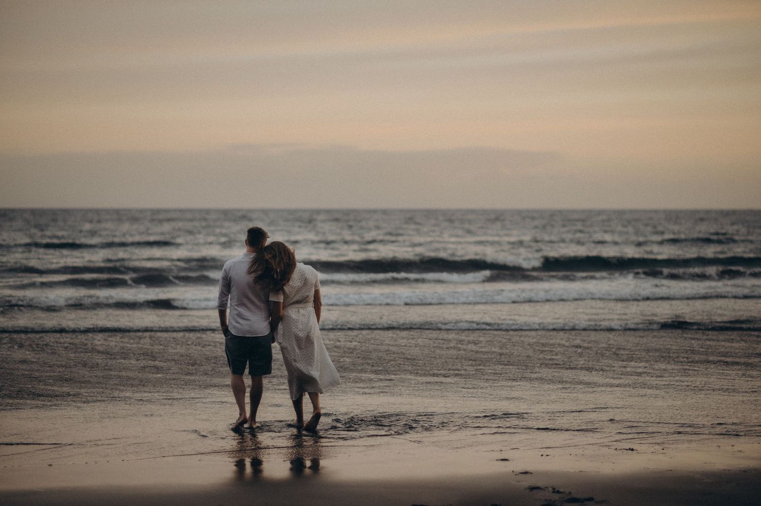 Young couple standing on Playa de La Tejita beach in Tenerife looking at the Atlantic Ocean
