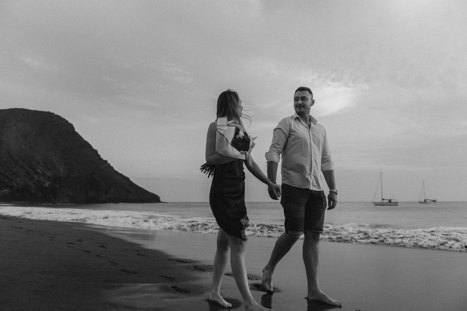 Couple walking hand-in-hand at sunset with Montaña Roja in background, Playa de La Tejita, Tenerife