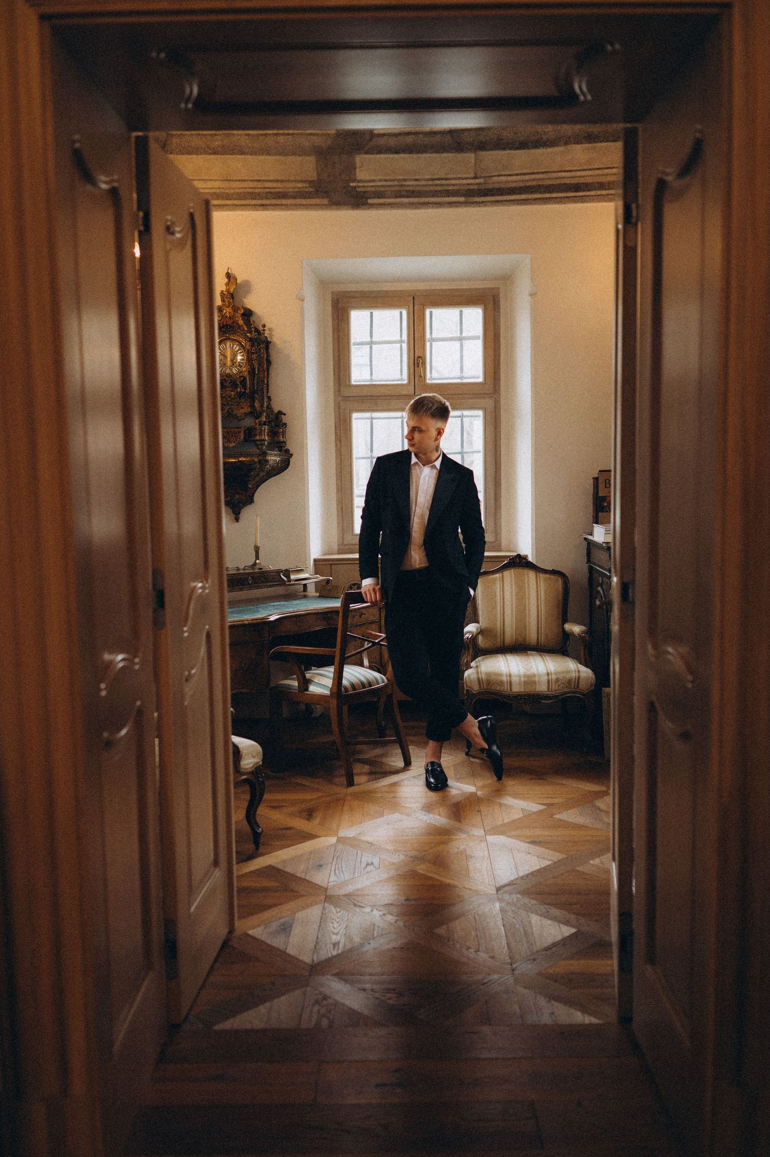 Groom walking through large entrance doors during a cinematic wedding moment.