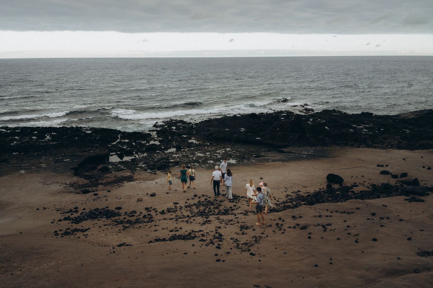 Distant shot of family as a single line on rocks with majestic Atlantic and sky, Tenerife