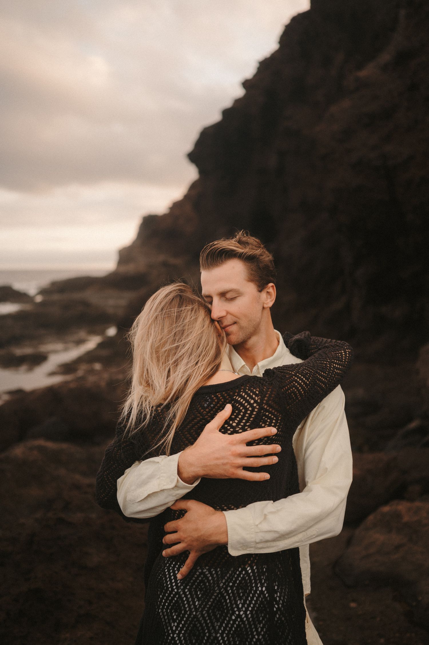 Young romantic couple holding each other tightly in an embrace during a photoshoot, sharing a loving moment in Tenerife