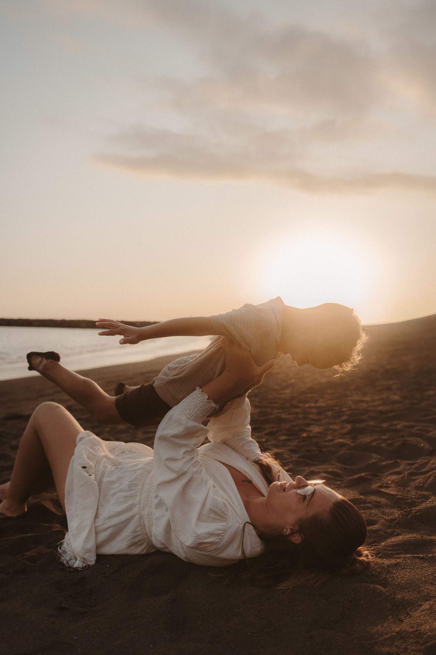 Emotional family photoshoot of mom and son on the seaside at golden hour