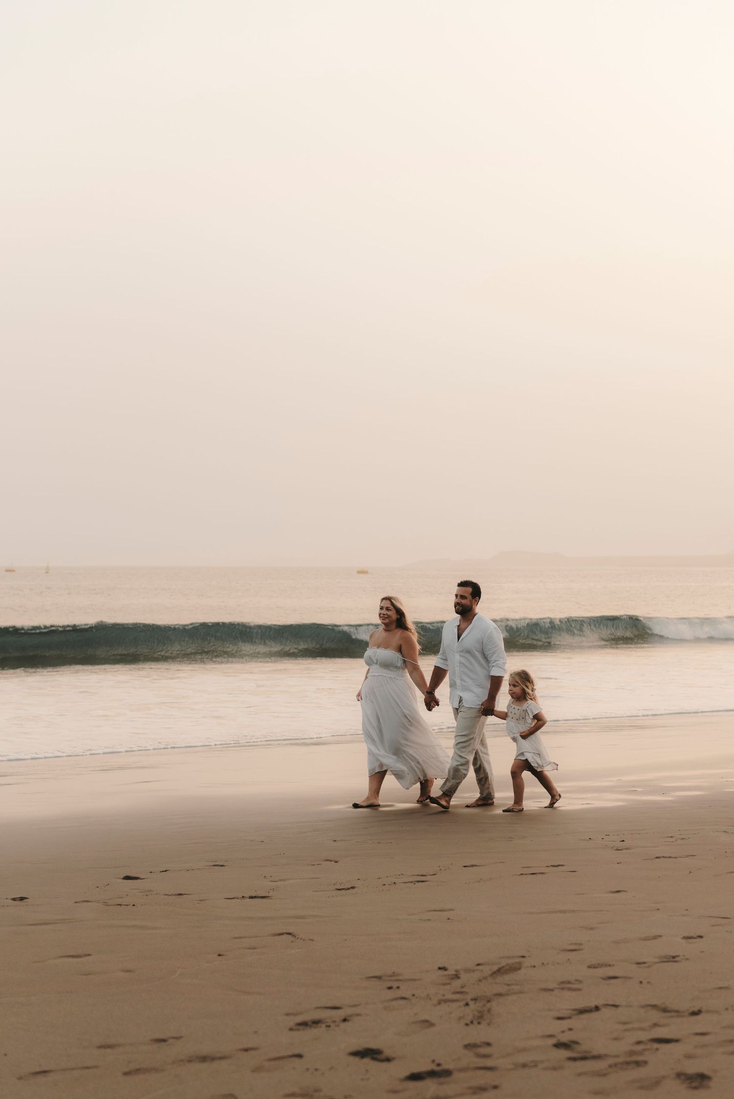 Wide shot of family of three walking and playing on Playa de la Tejita, Tenerife