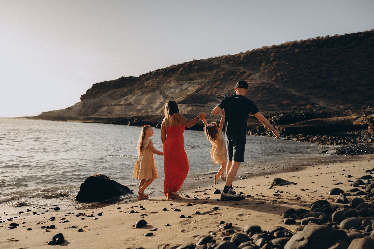 Parents and children sharing moments during a sunset photoshoot at Playa de los Morteros