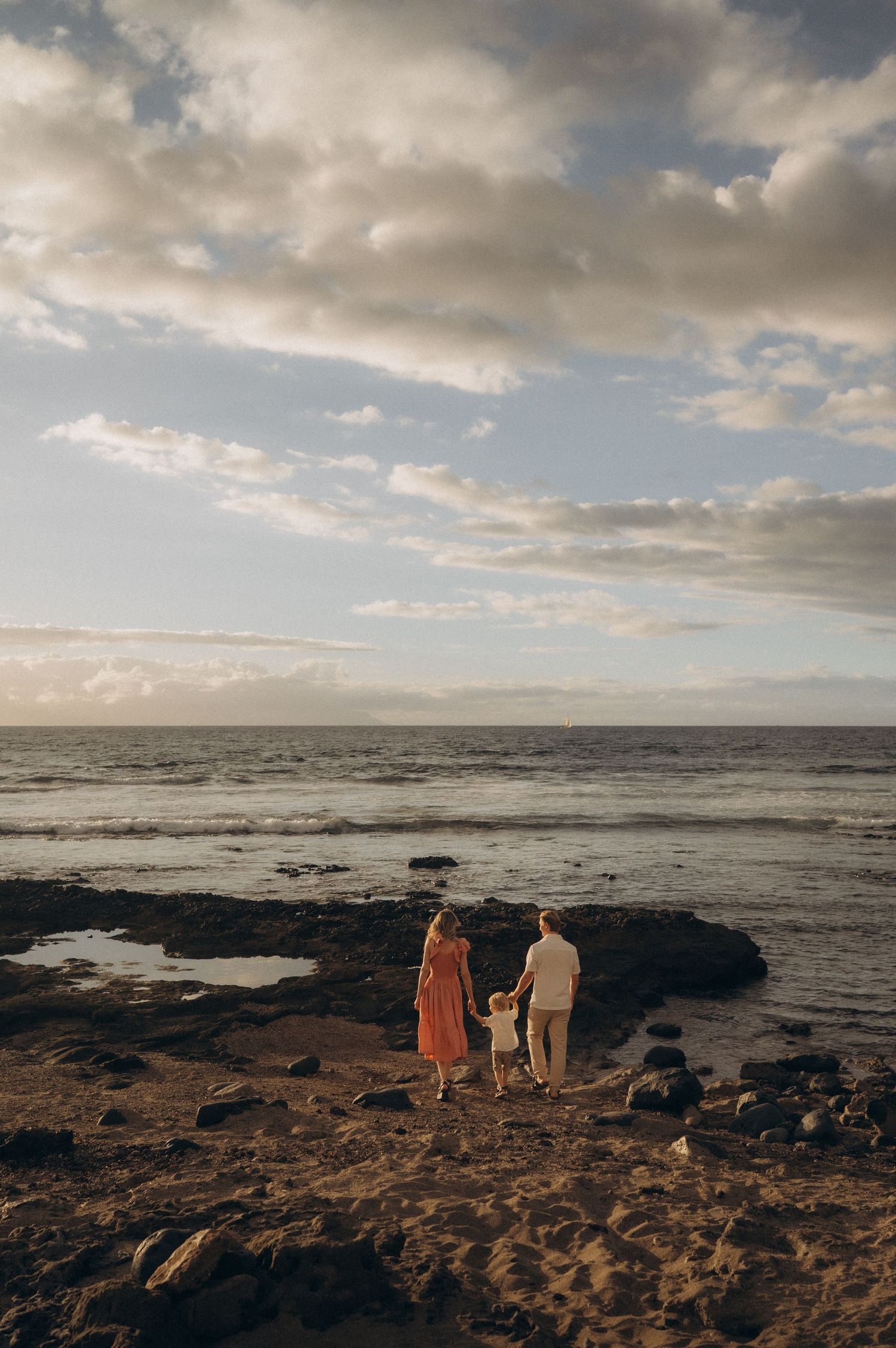 Couple and young child enjoying hidden beach spot with rocks in Las Americas, Tenerife