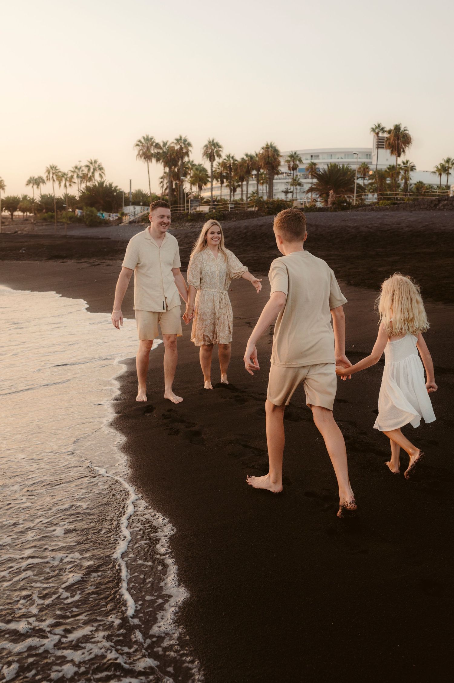 Family moment with children in front, parents holding hands behind, sunset in Playa del Duque Tenerife