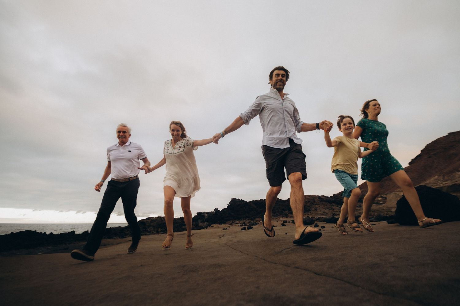 Large family running hand in hand toward the camera during fun Tenerife photoshoot