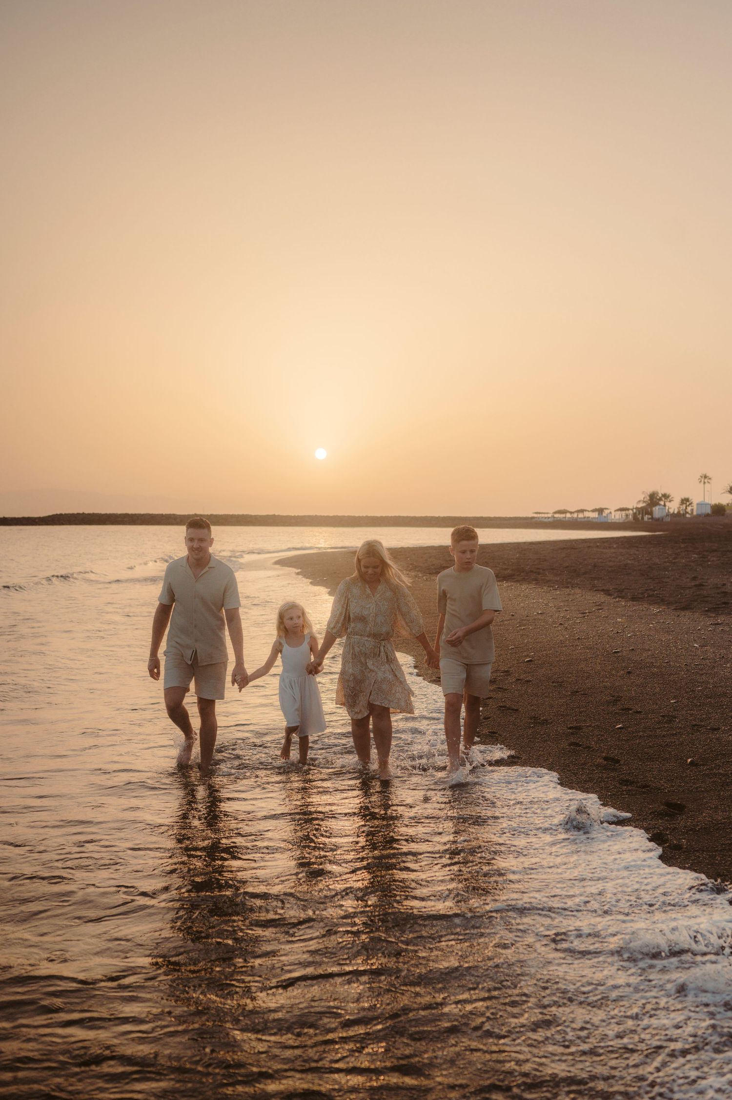 Family moment on volcanic beach enjoying sunset on Playa del Duque, Tenerife