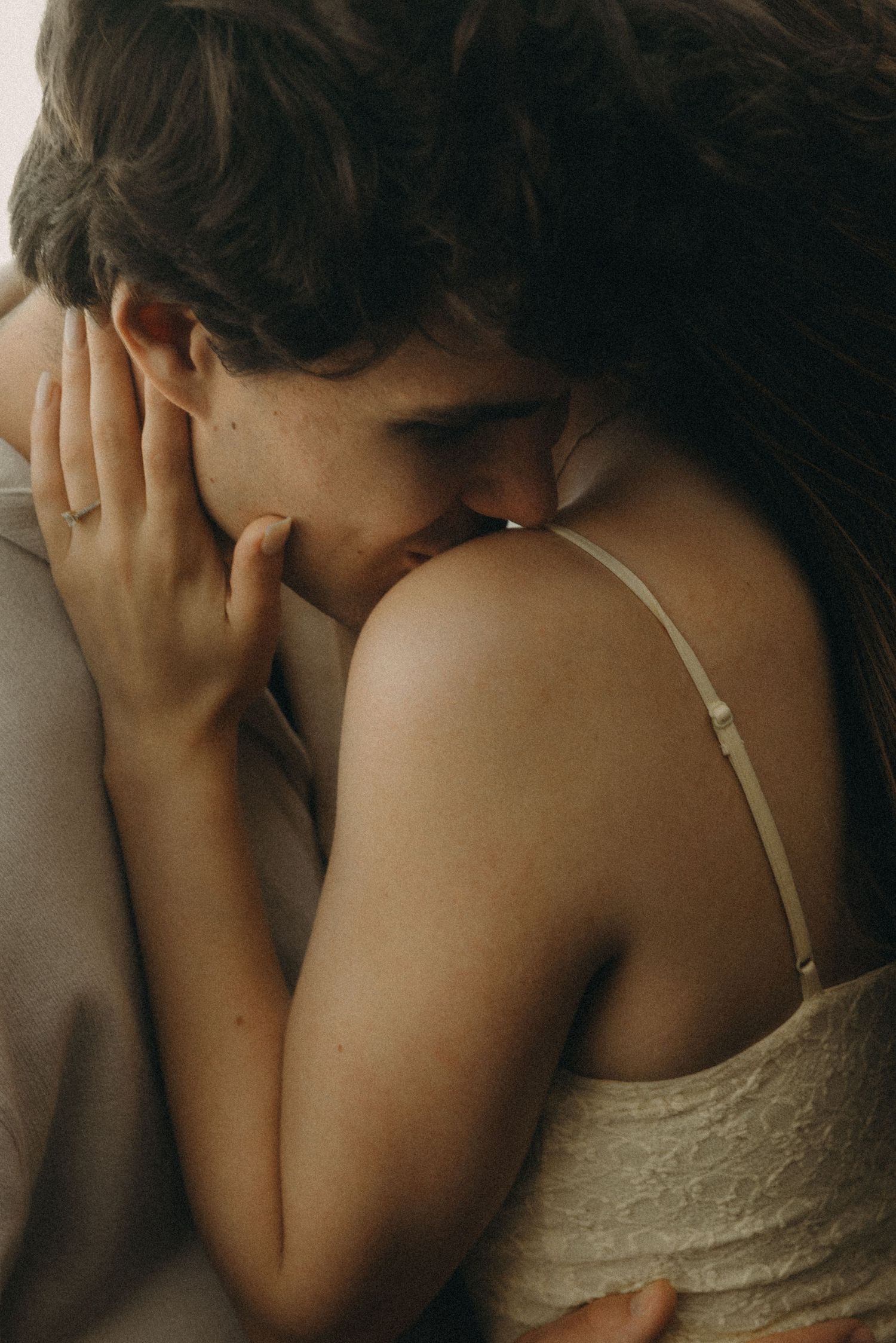 Two people sharing an intimate embrace, with a tender moment of closeness and affection captured in soft, warm tones.