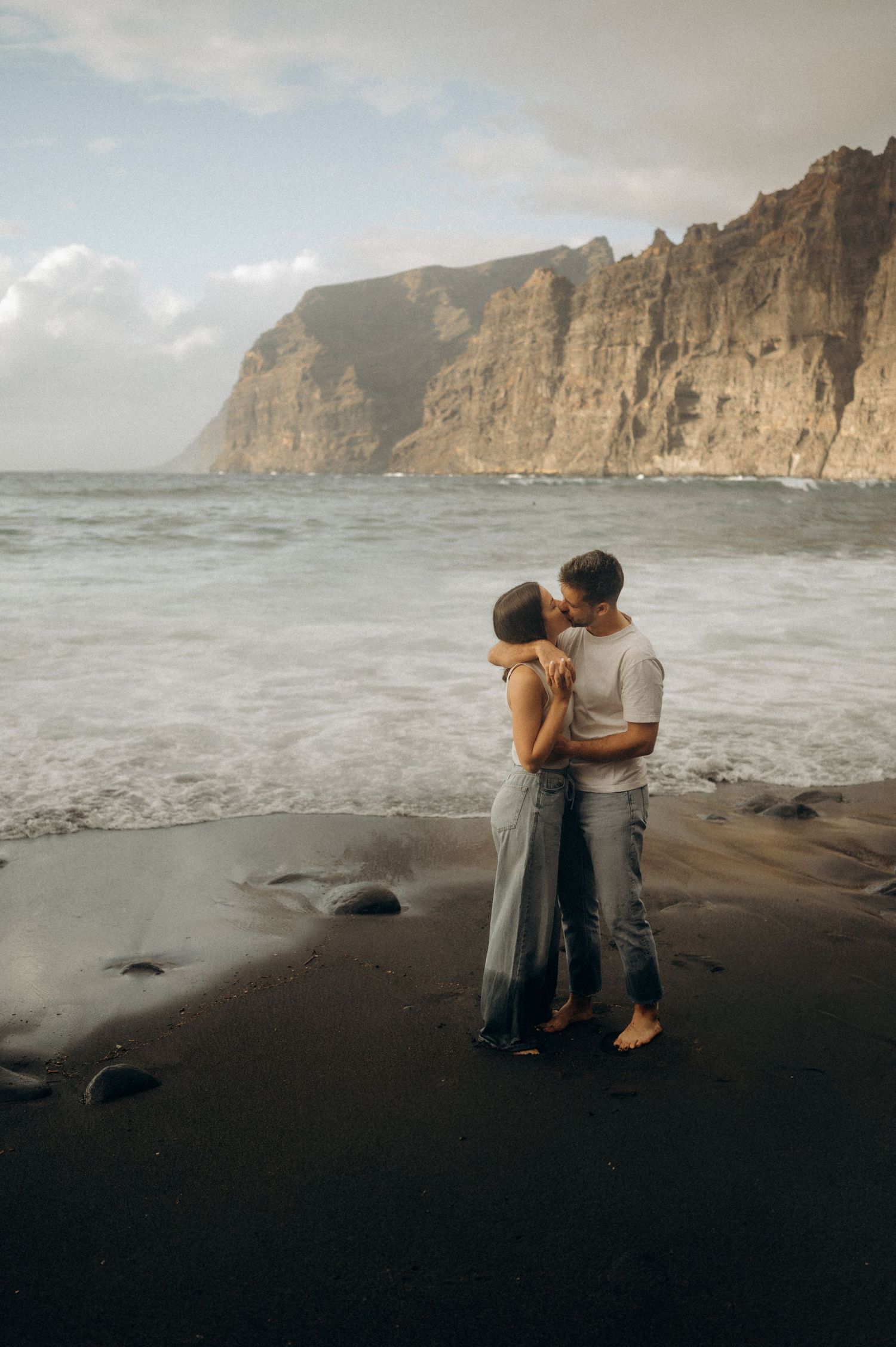 Romantic couple holding each other with majestic Los Gigantes cliffs in background, Tenerife