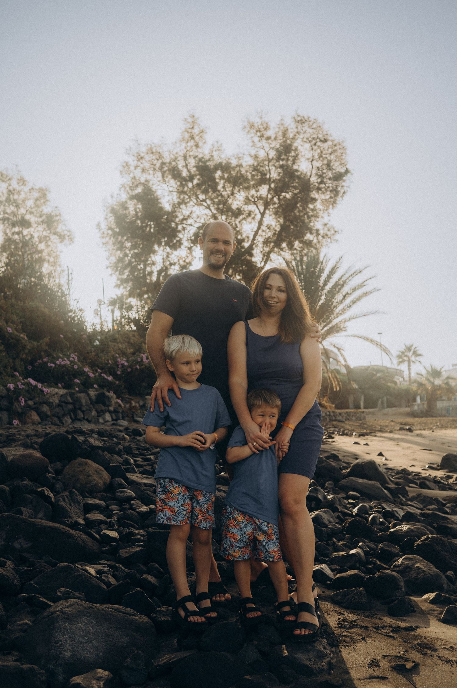 Parents and two children posing for a tender group photo in the shade of a palm tree on Playa Fañabé