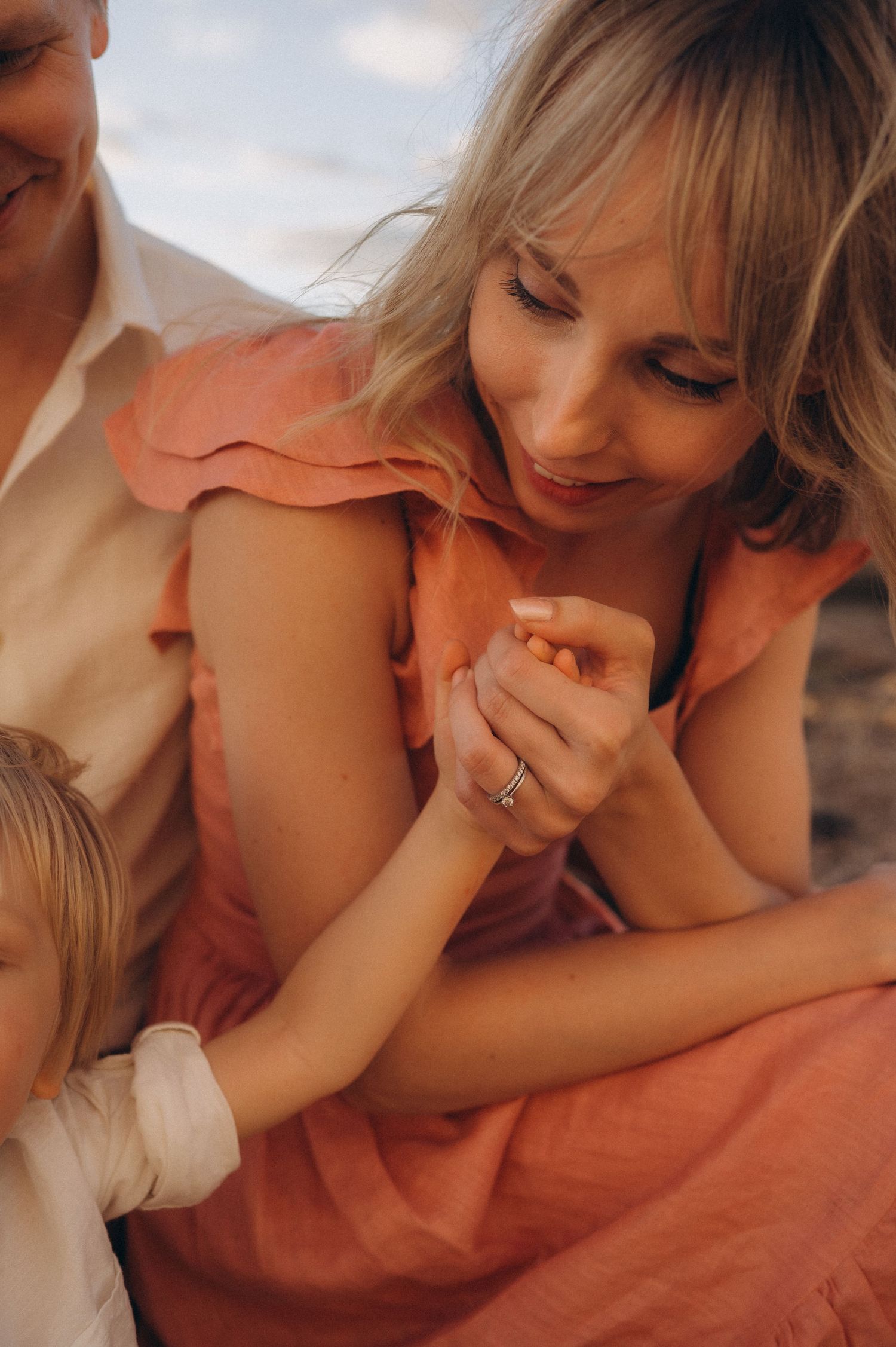 Close-up of toddler giving hand to mom while dad sits behind, family in embrace, Las Americas