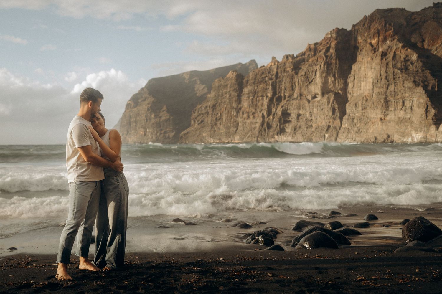 Loving couple embracing with Los Gigantes cliffs behind on Playa de Los Guíos, Tenerife