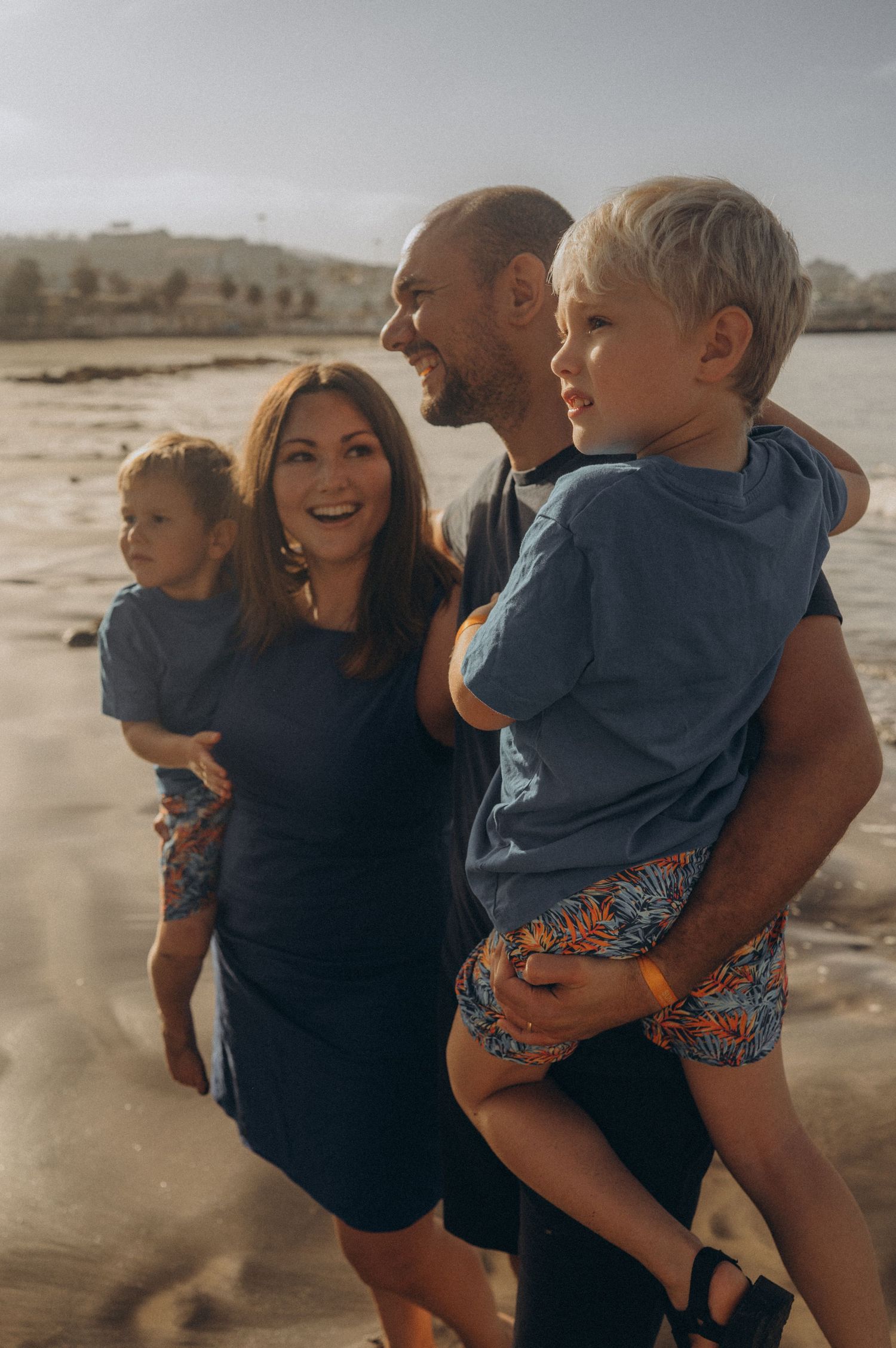Parents holding their two sons in a classic family portrait during morning light at Playa Fañabé