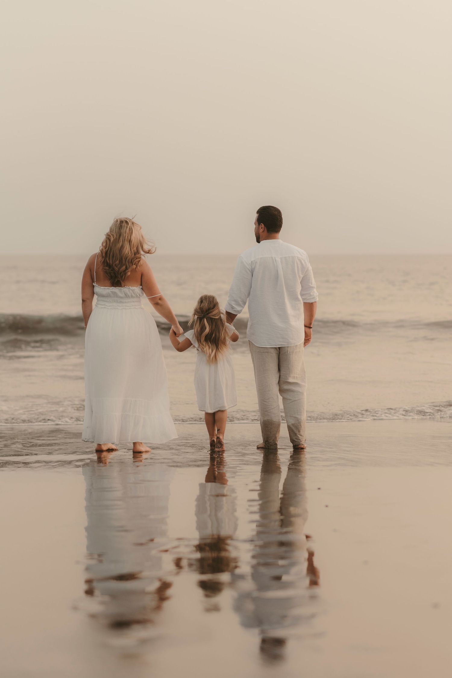Tender moment of a family observing the ocean together from behind, hand in hand at Playa La Tejita