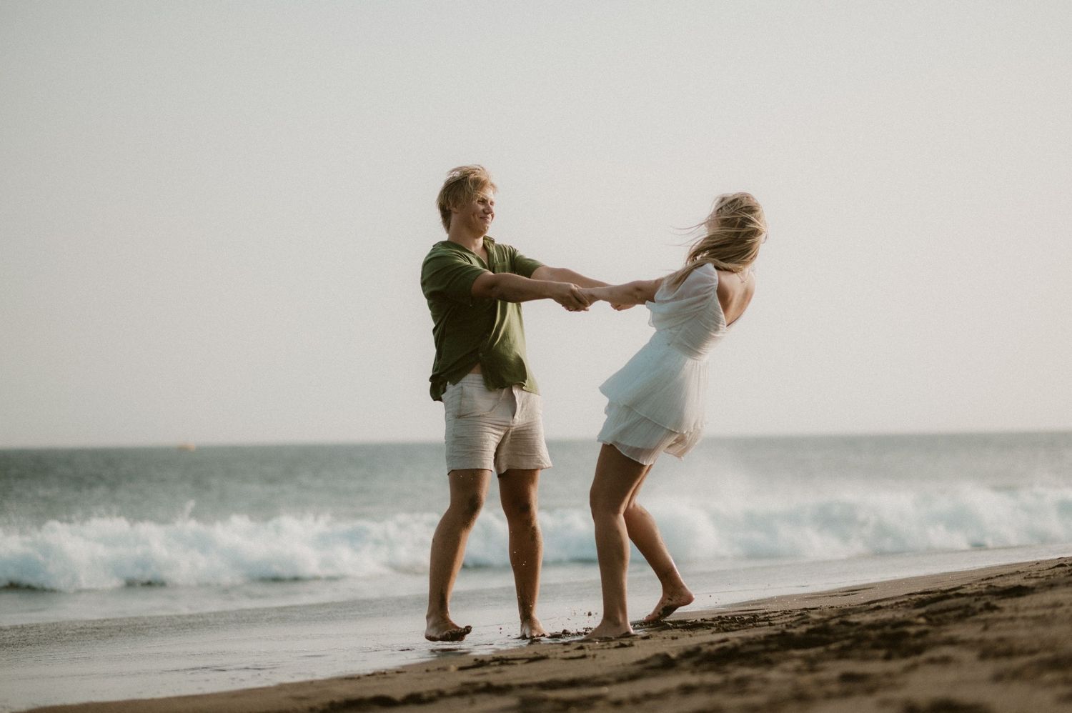 Couple twirling together on Playa Tejita sand, ocean waves.