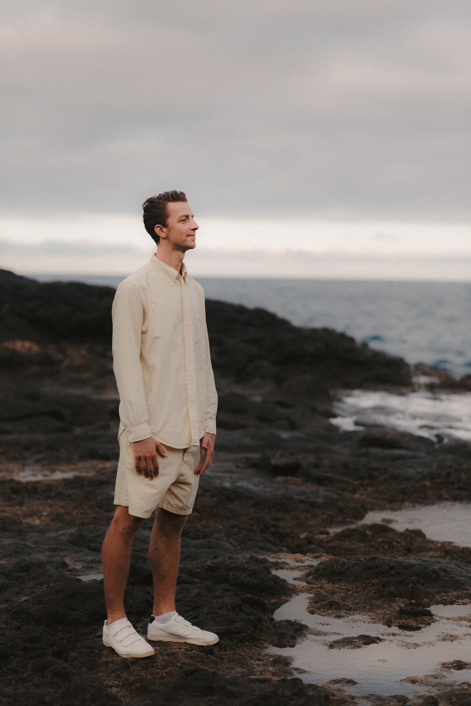 Close-up of a man standing on the rocks by the ocean, gazing into the distance at his beloved during a photoshoot in Tenerife