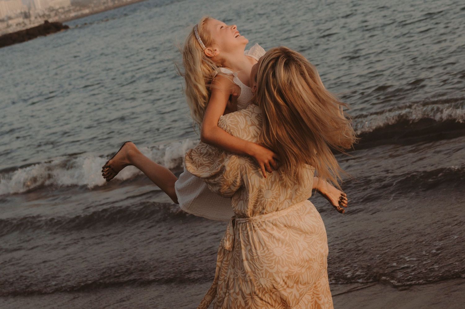 Family moment with mom holding young girl on volcanic sand, Tenerife
