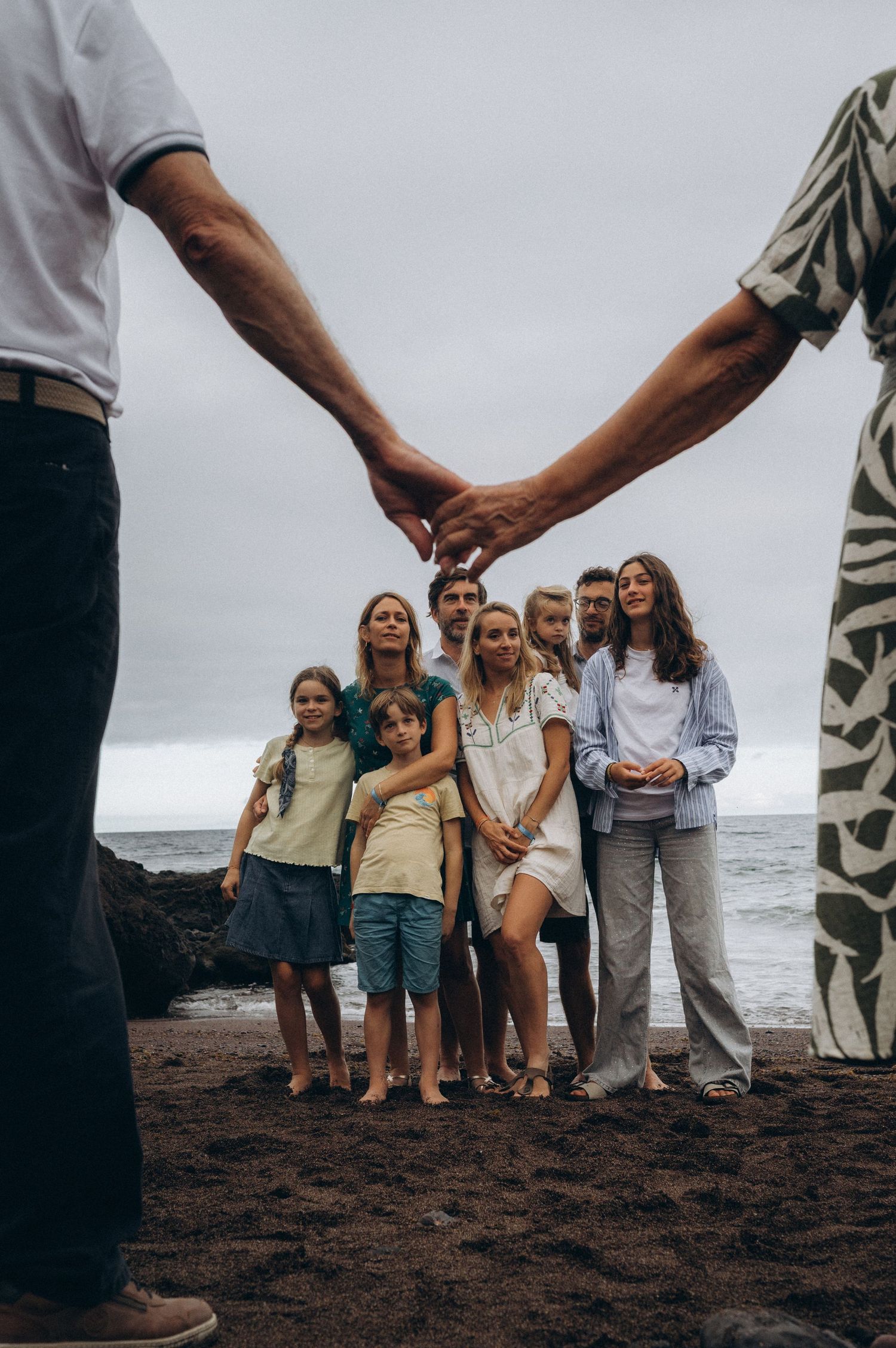 Elderly couple stretching arms while family stands below on black beach at Los Refugios, Tenerife