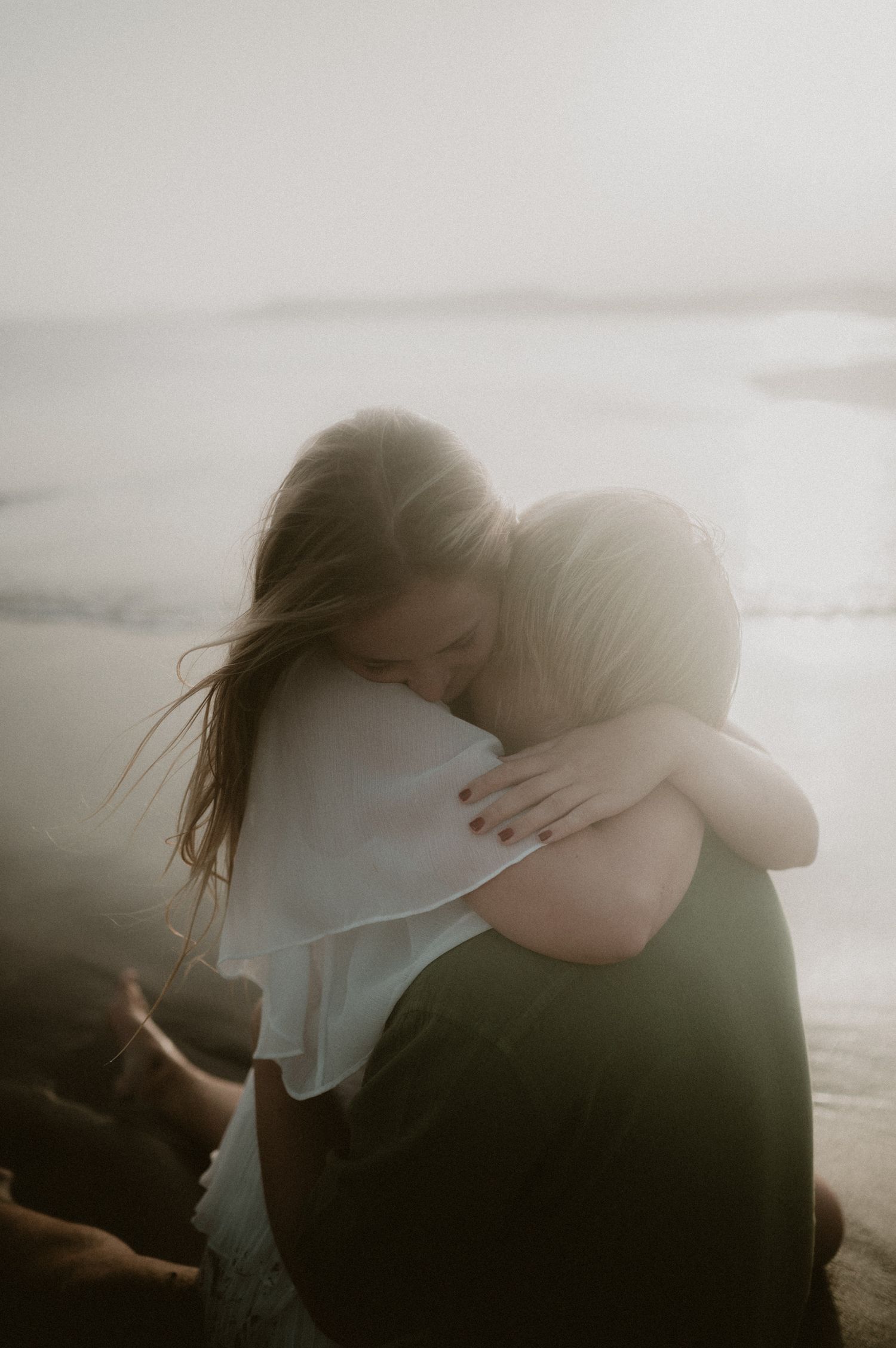 Couple embracing in the ocean at Playa Tejita with sunset lighting and waves behind them, Tenerife couples photoshoot