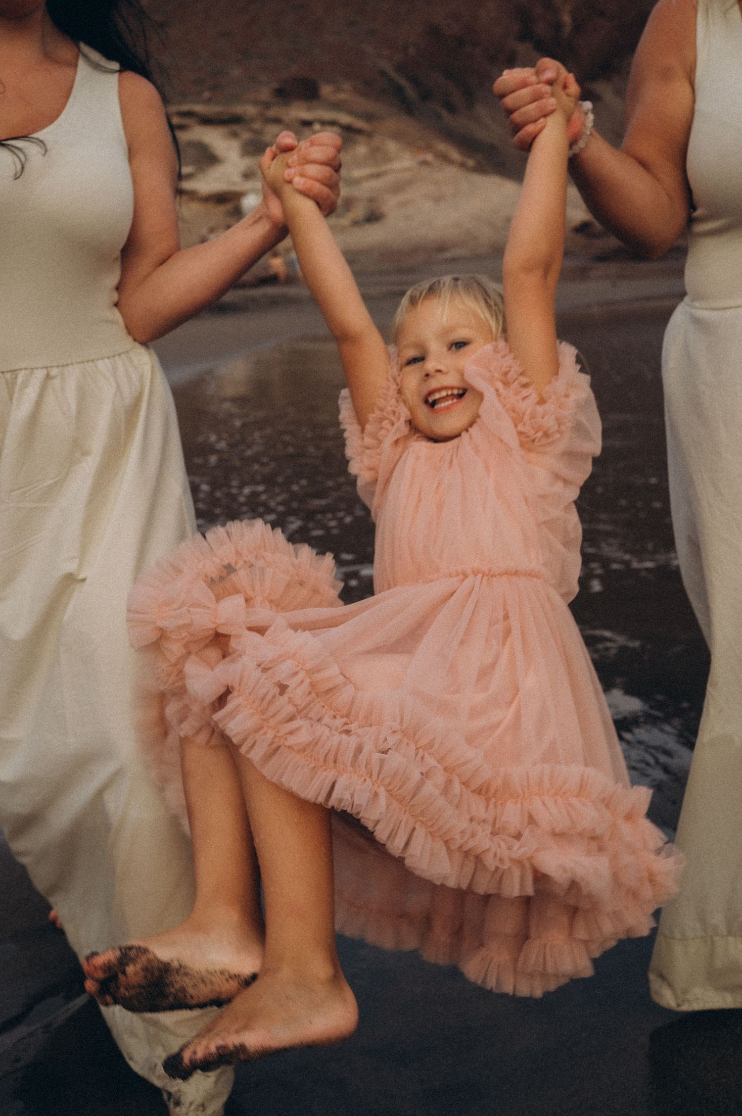 Close-up of young girl being lifted and swung in the air by family, Playa La Tejita Tenerife