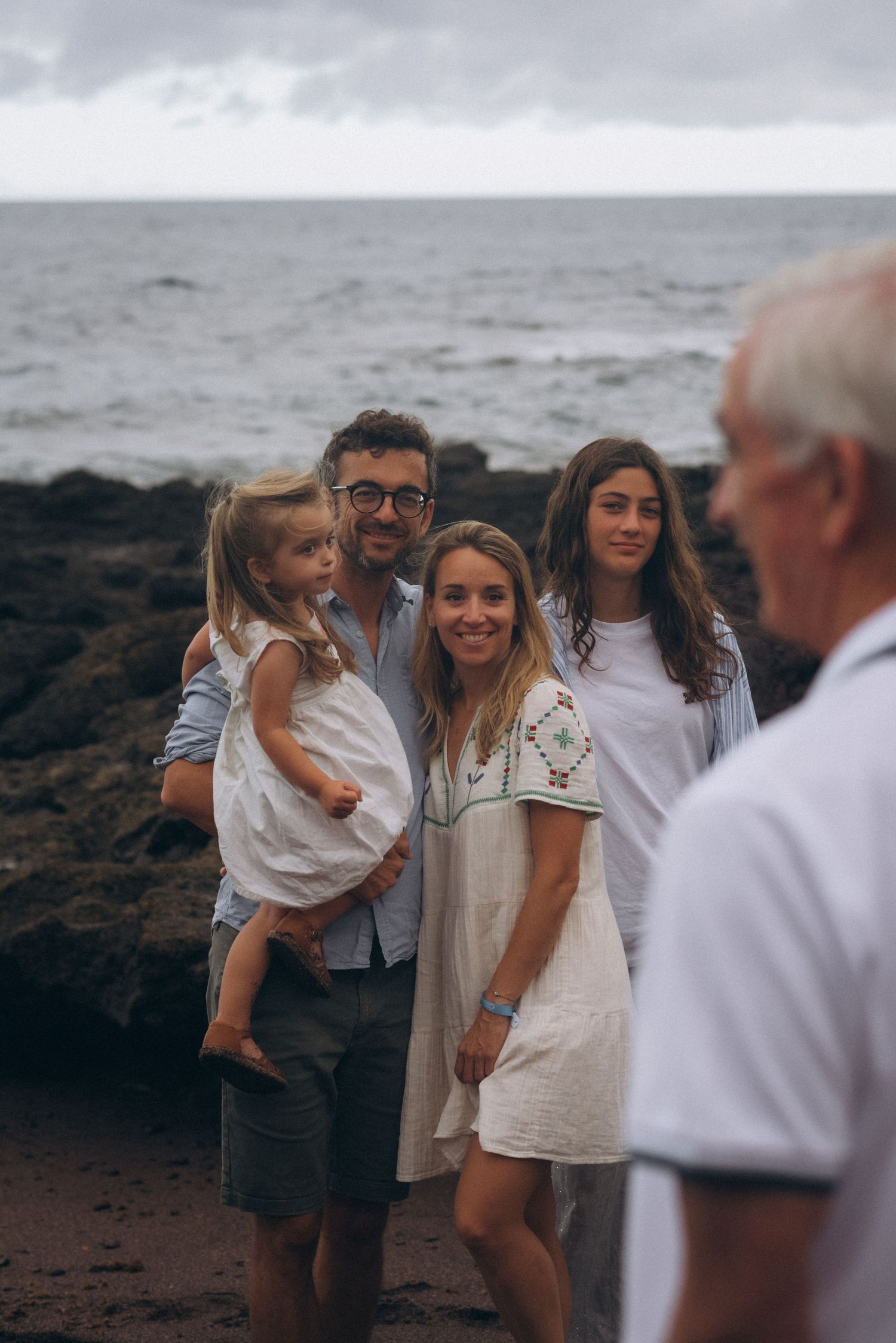 View from behind grandfather of his family posing on black sand beach at Los Refugios, Tenerife