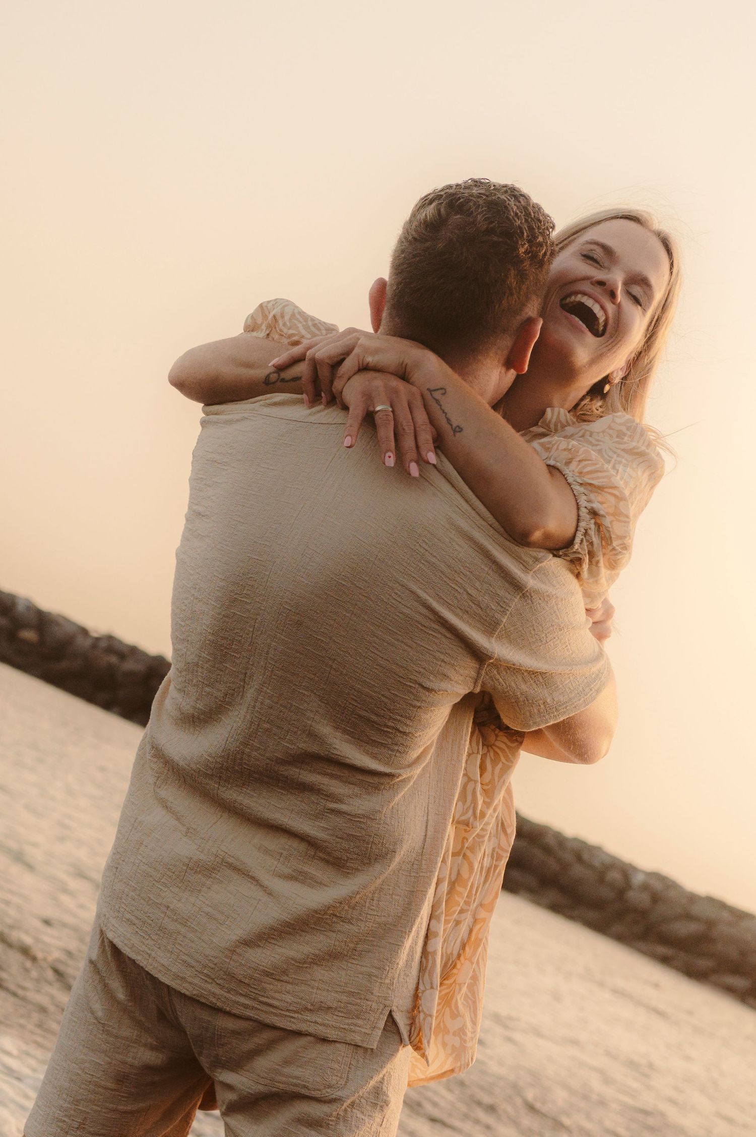 Husband lifting laughing wife in arms with sunset in background, Tenerife
