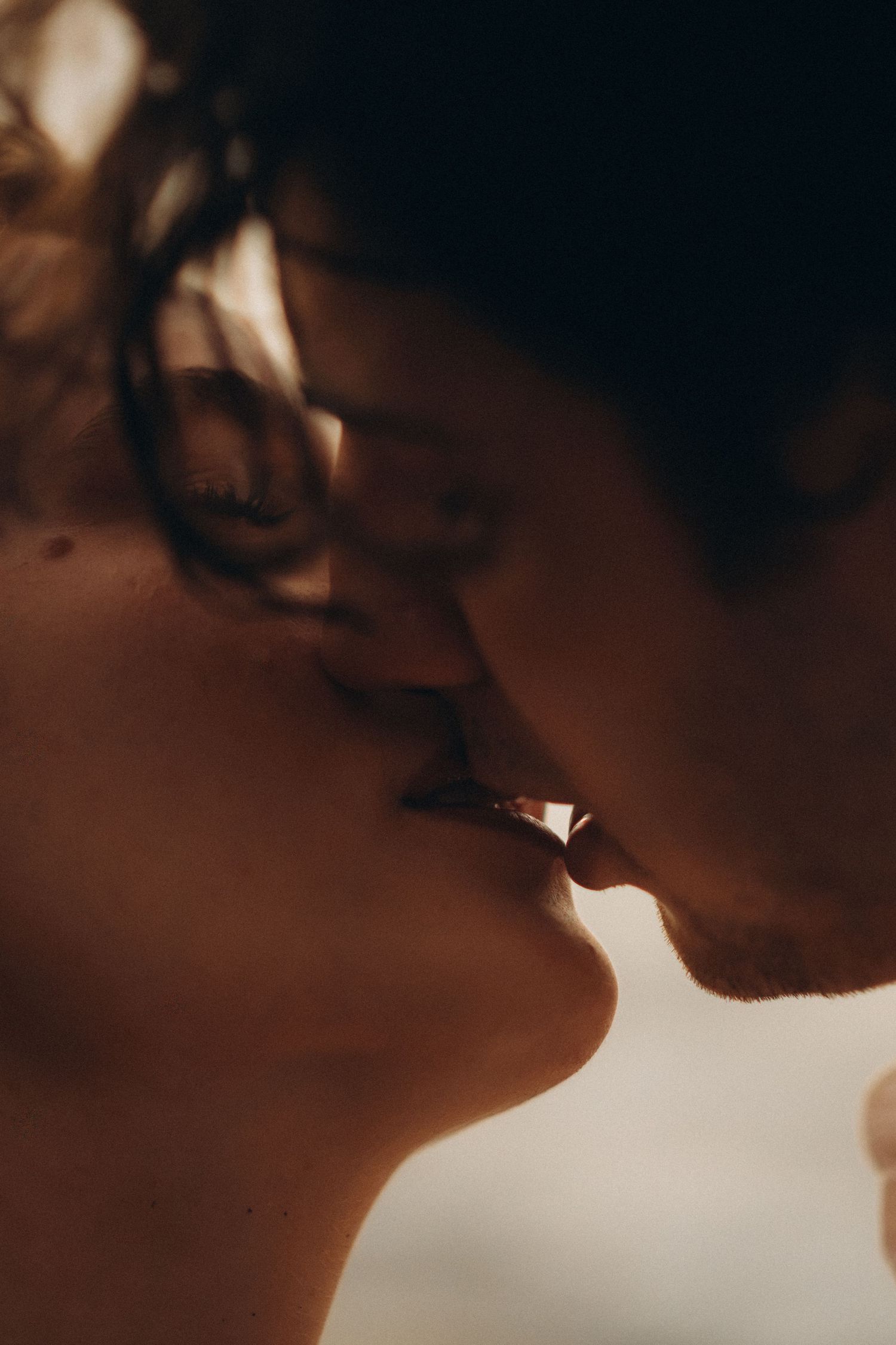 Close-up of two people sharing a romantic kiss, bathed in warm, soft light.