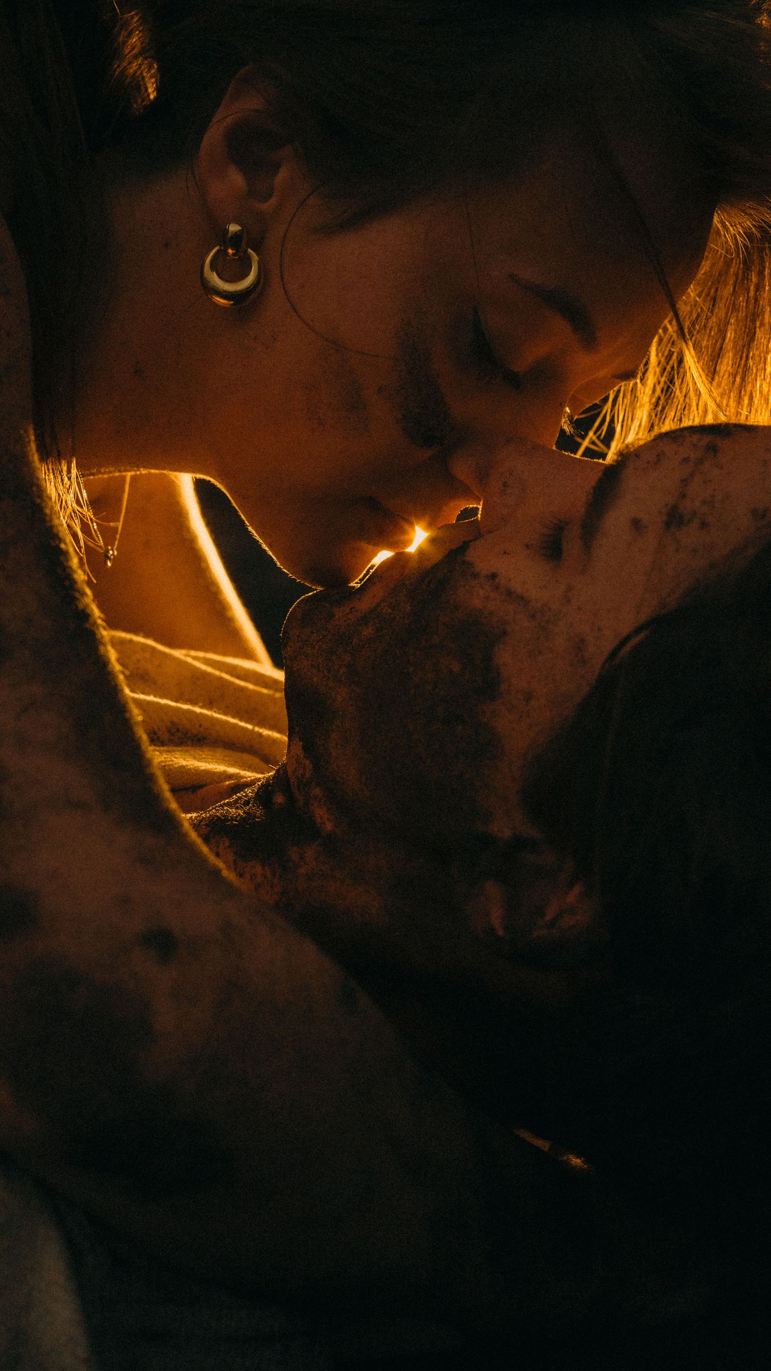 A couple shares an intimate moment in warm golden light, their faces close together in a romantic near-kiss.