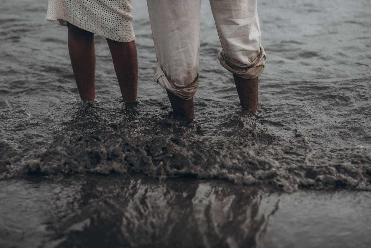 Romantic moment showing feet in shallow waves with reflections